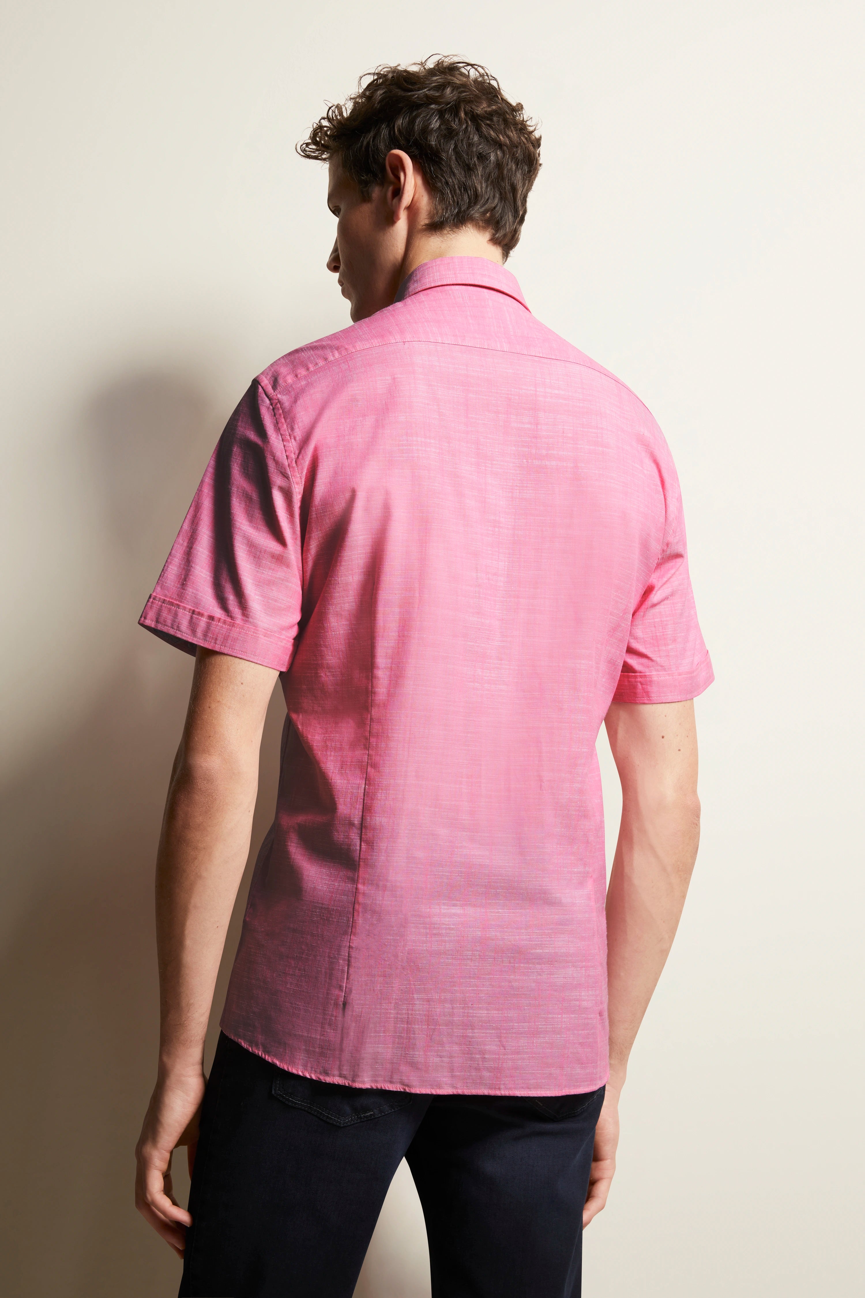 Model van achteren met roze bugatti overhemd, korte mouwen, gecombineerd met donkere broek.