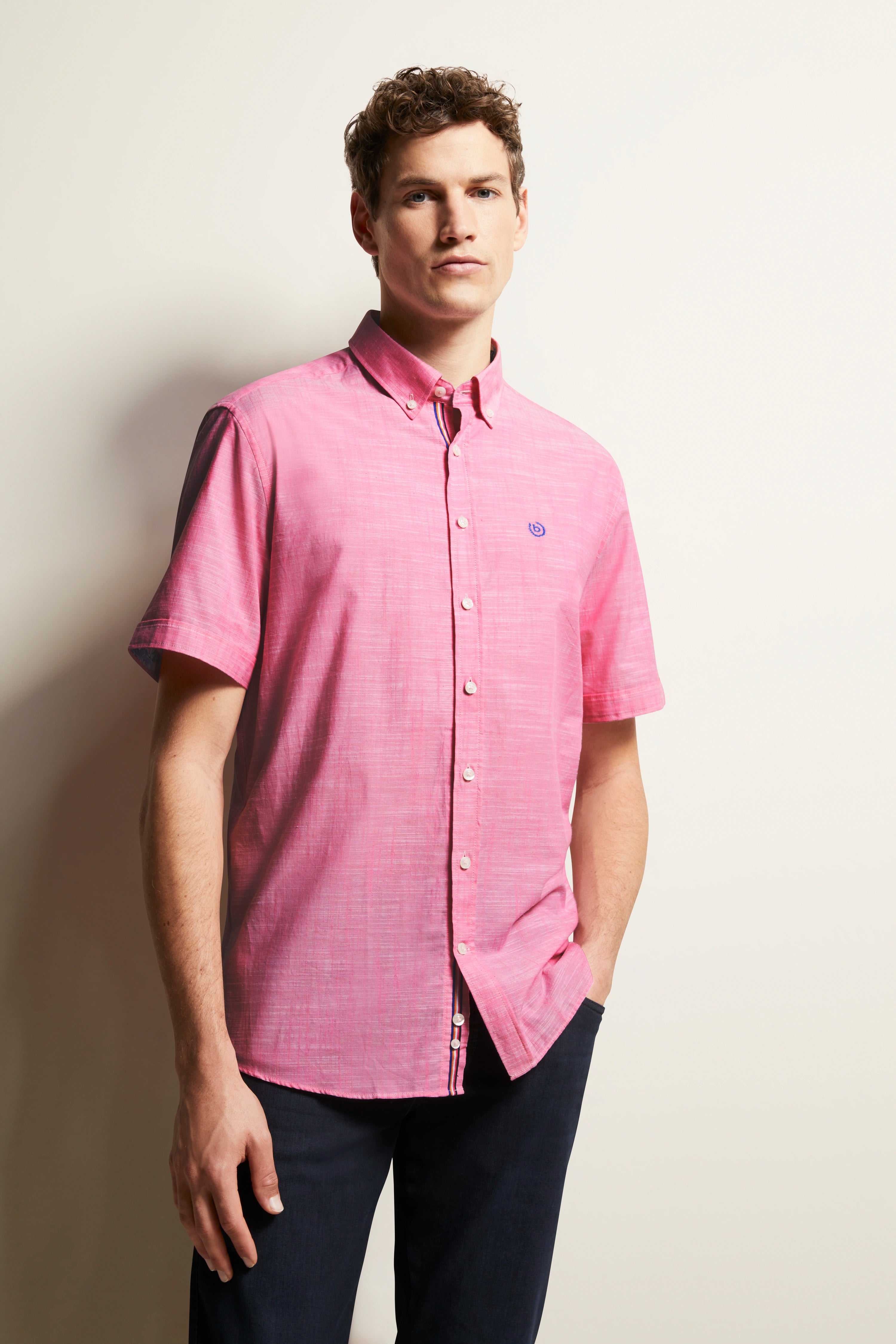 Model in rosa bugatti-Hemd, Kurzarm, Jeans, lässige Pose, stilvoll und zeitlos.