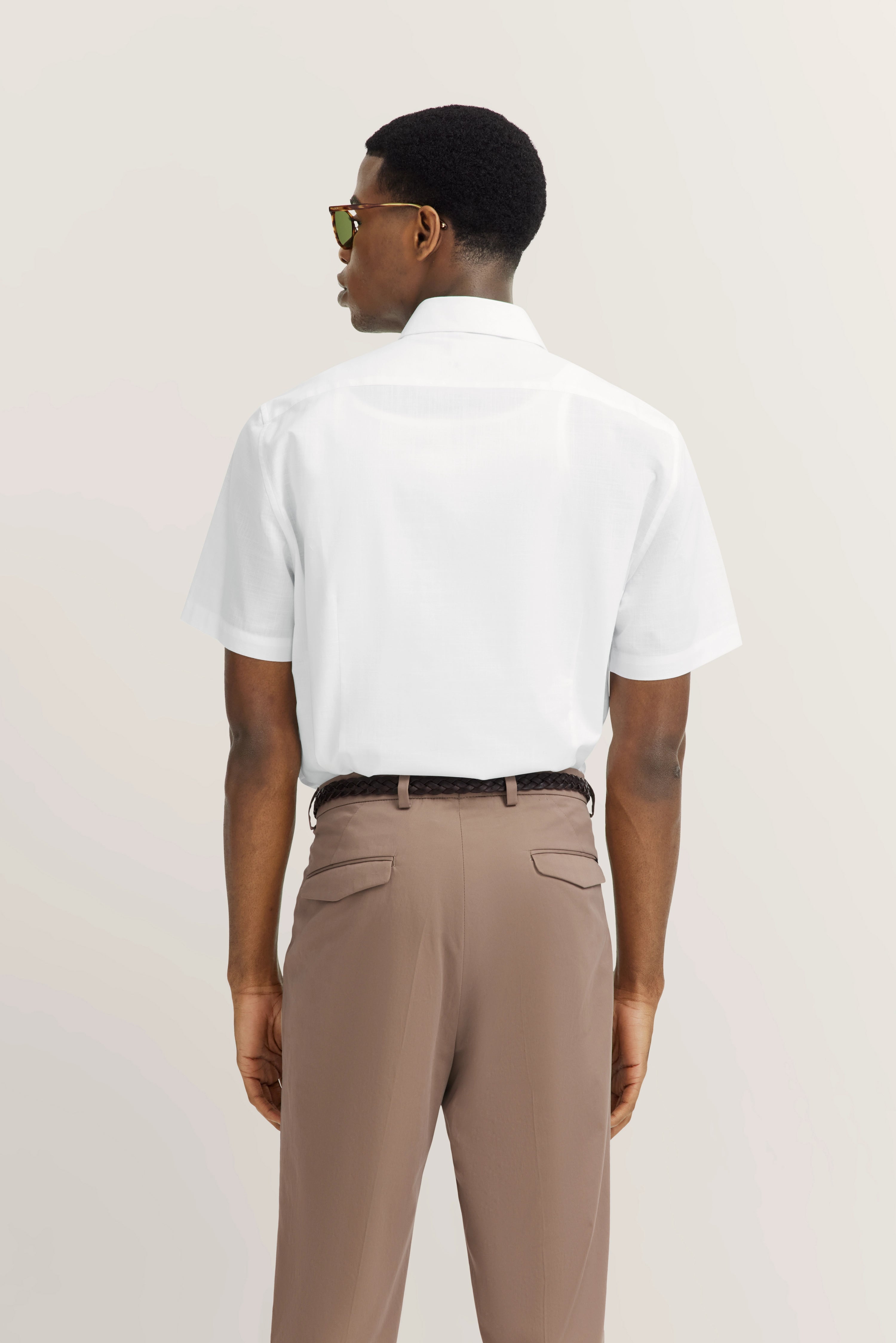 Wit kort mouw shirt, beige broek, model van achteren.