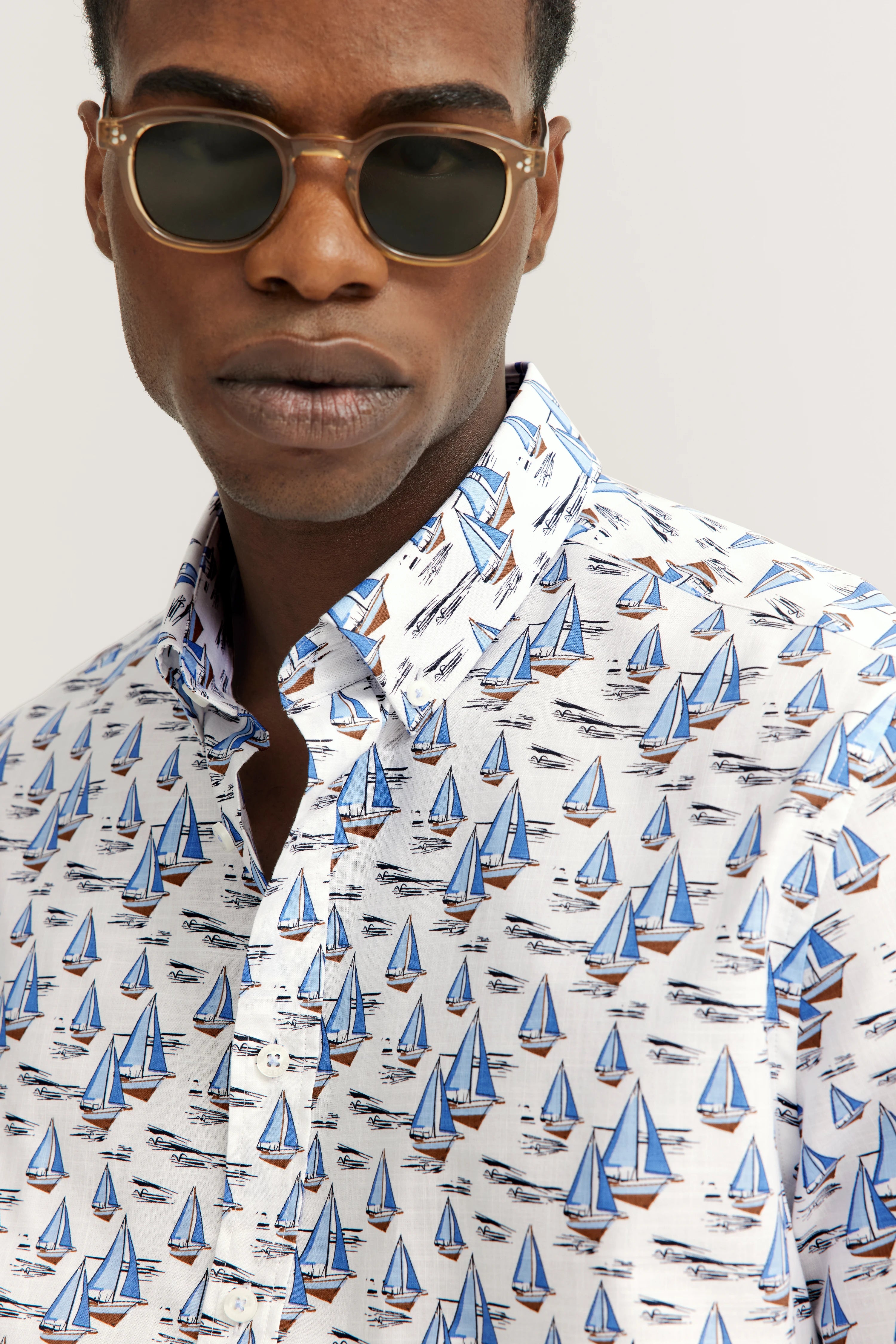 bugatti Hemd mit Segelboot-Print in Blau-Weiß, Modelbild mit Sonnenbrille, lässige Pose.