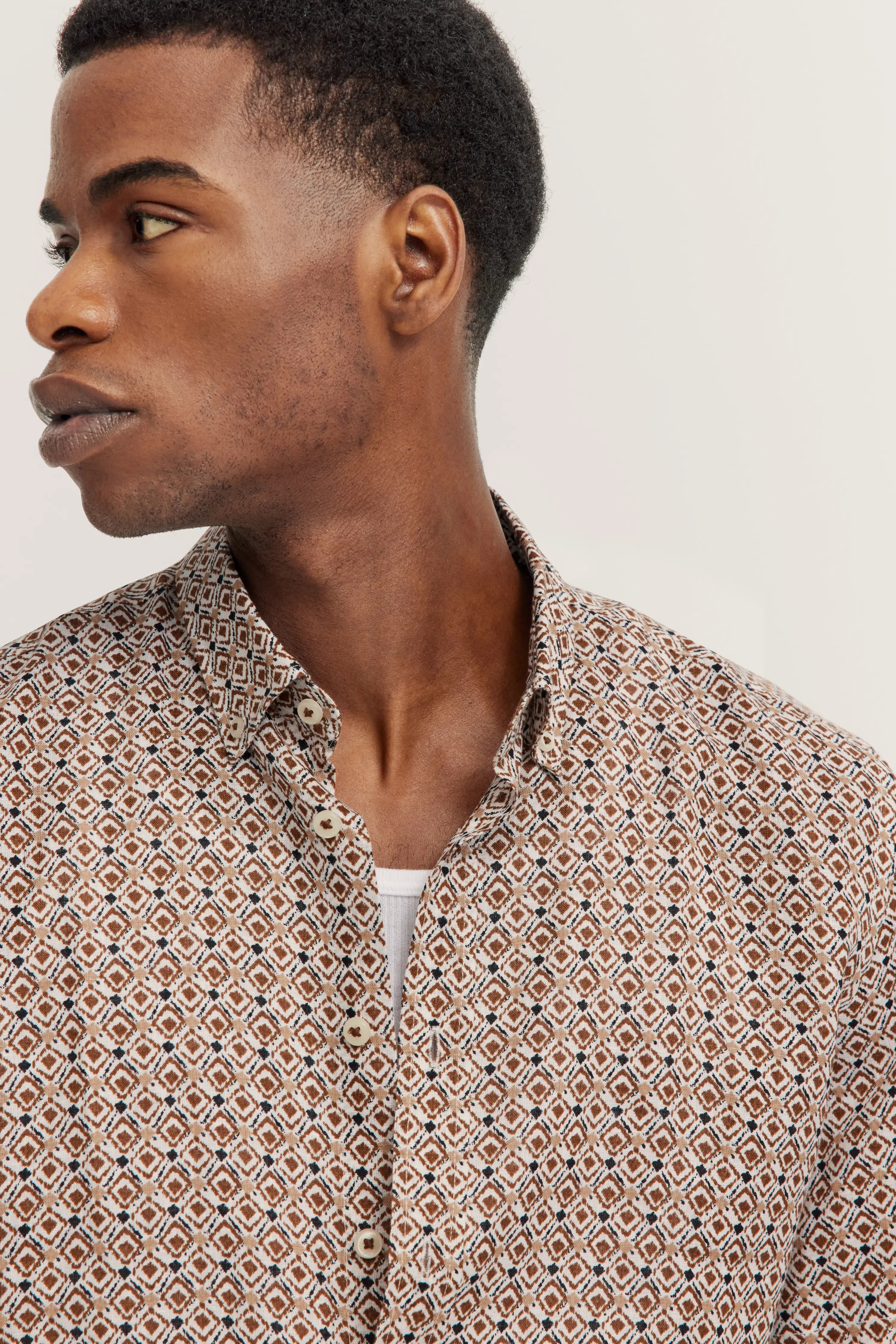 Kurzarmhemd mit geometrischem Muster in Beige und Weiß, Rückansicht. Büstenbild.