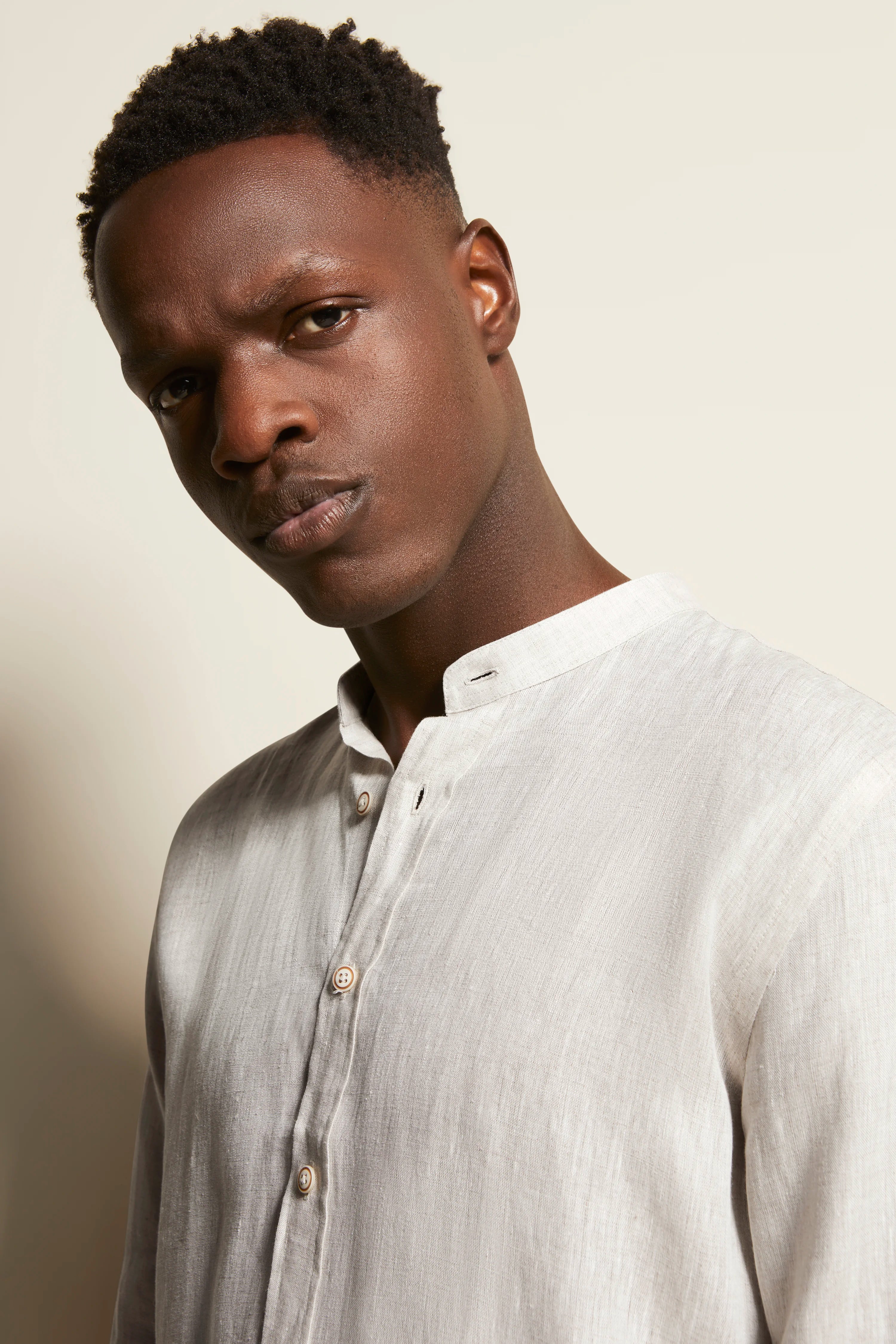 Elegant model image: Light linen shirt, beige pants. Back view, casual. Pose conveys serenity.