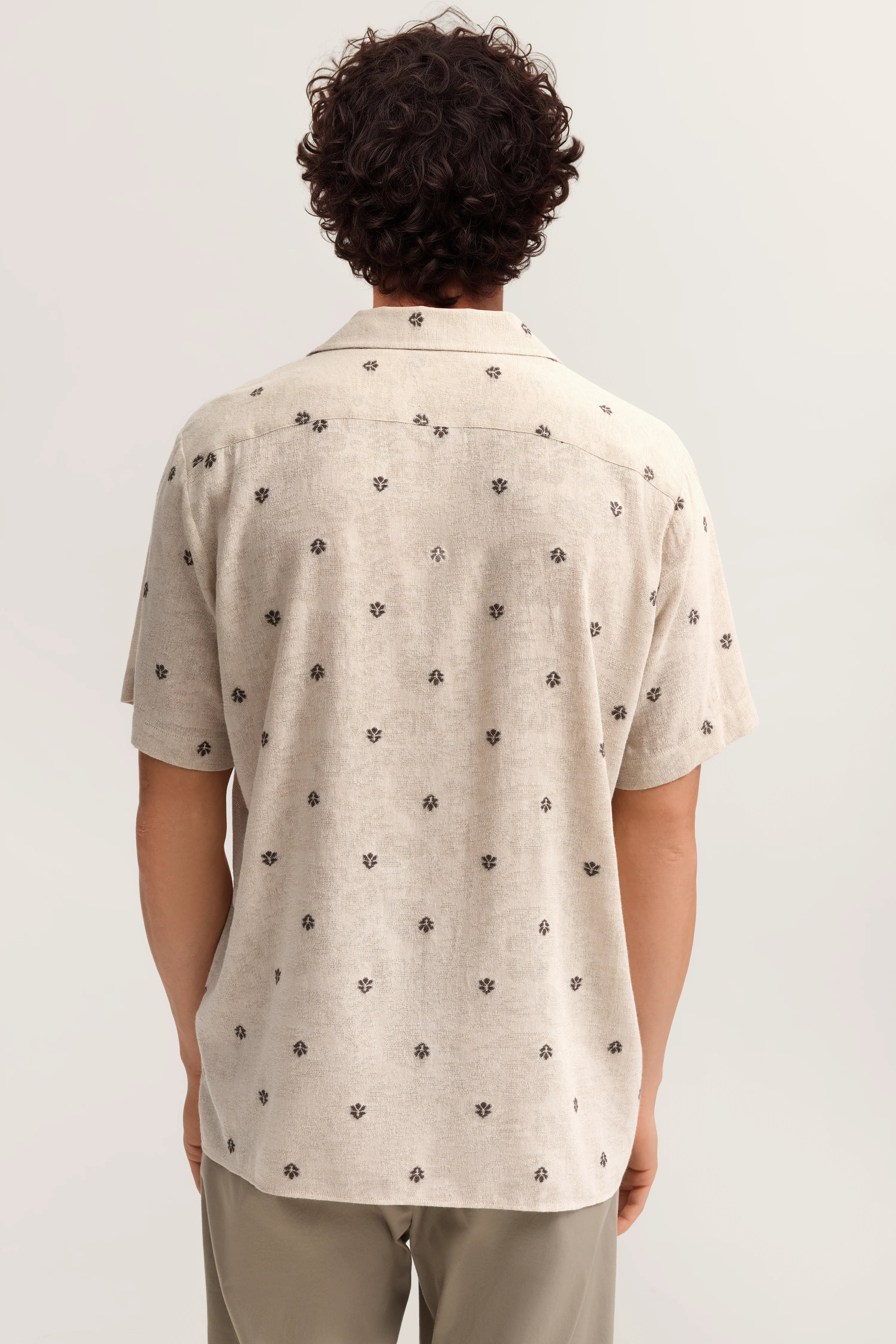 Beiges Kurzarmhemd mit schwarzem Muster, legeres Modelbild von hinten.