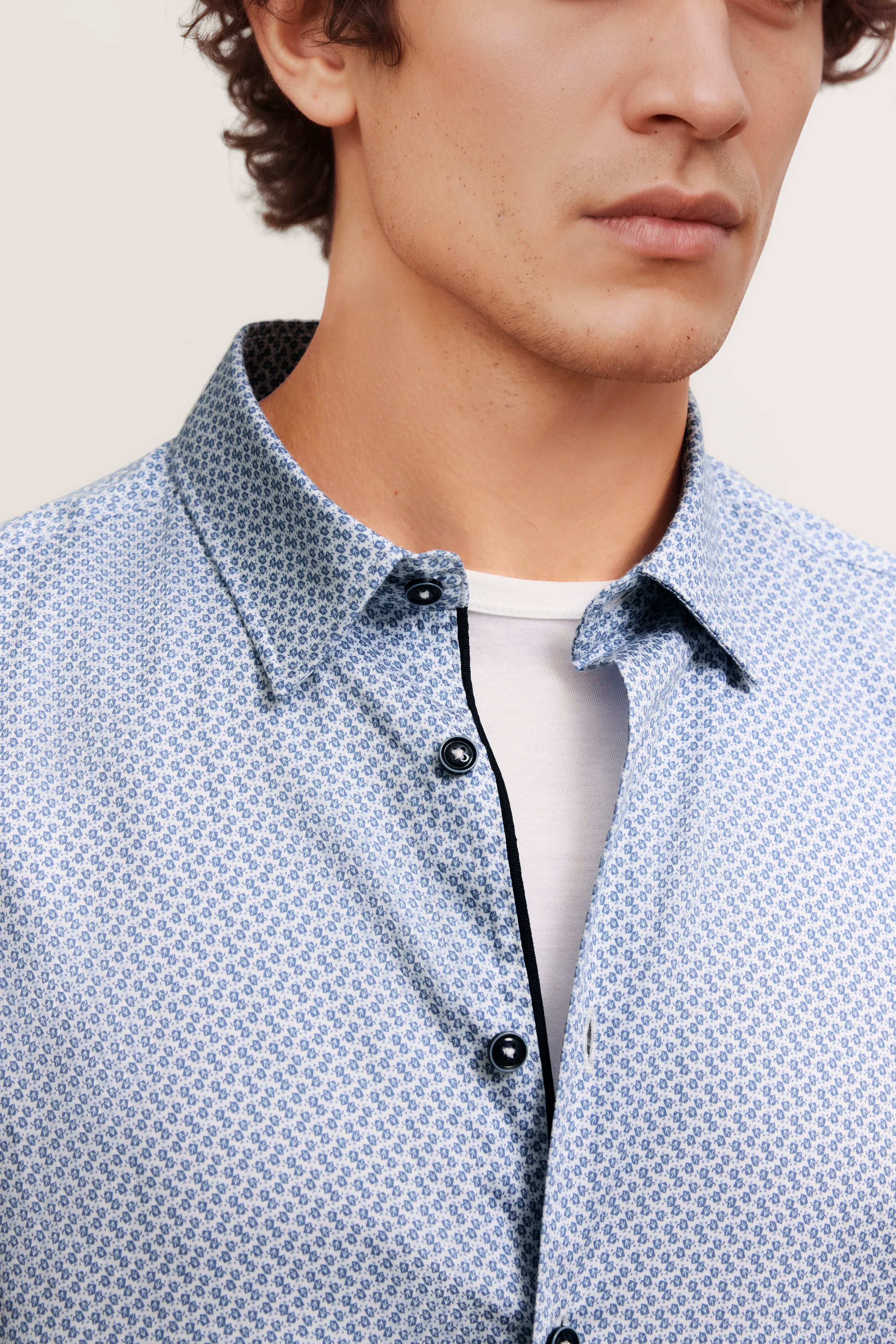 Büstenbild: Hellblau gemustertes Hemd von bugatti über weißem Shirt.