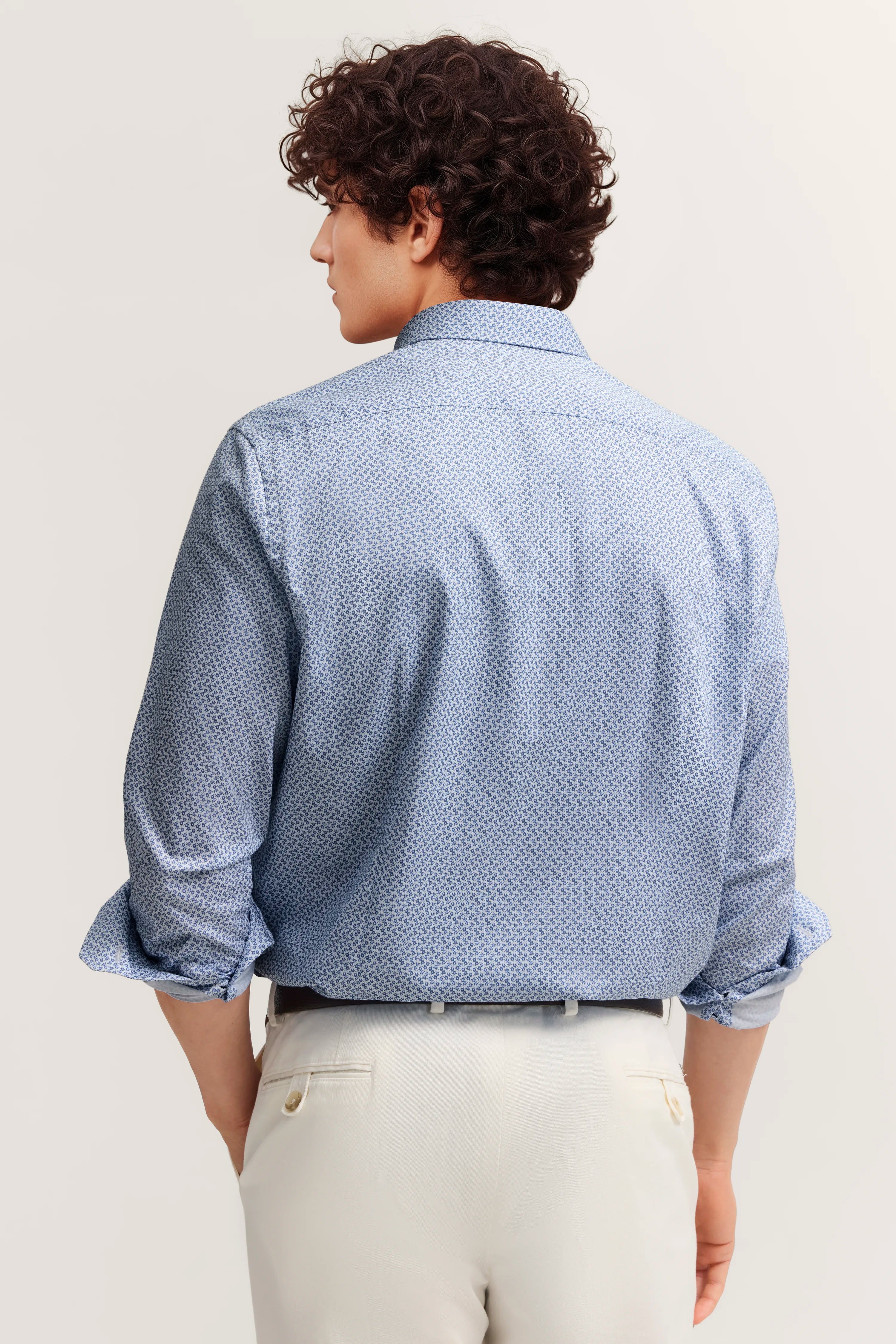 Blau gemustertes Hemd und weiße Hose, Rückansicht, Model mit entspanntem Posing.