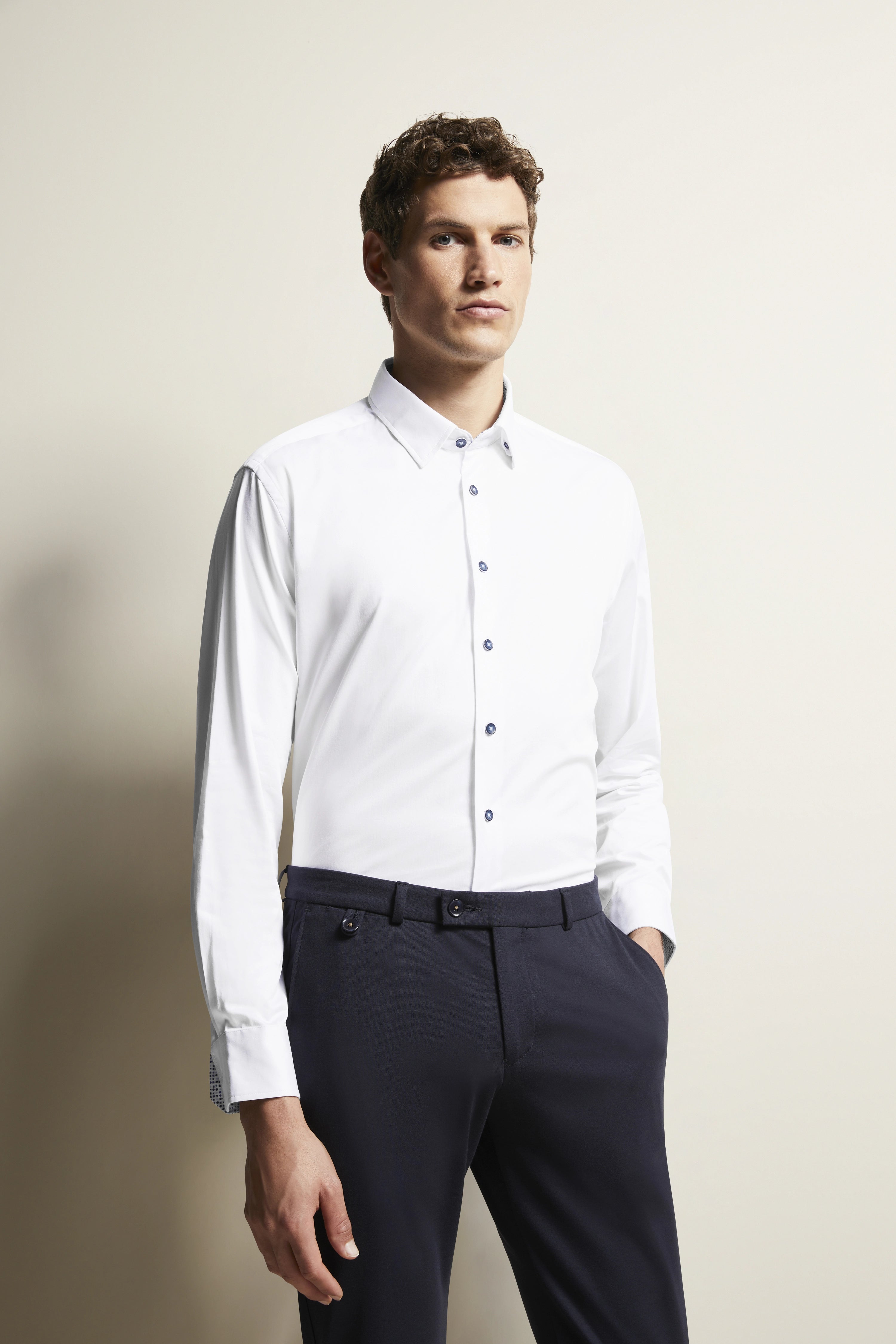 Wit overhemd, donkerblauwe broek, modelpose, ontspannen stijl, bugatti elegantie.