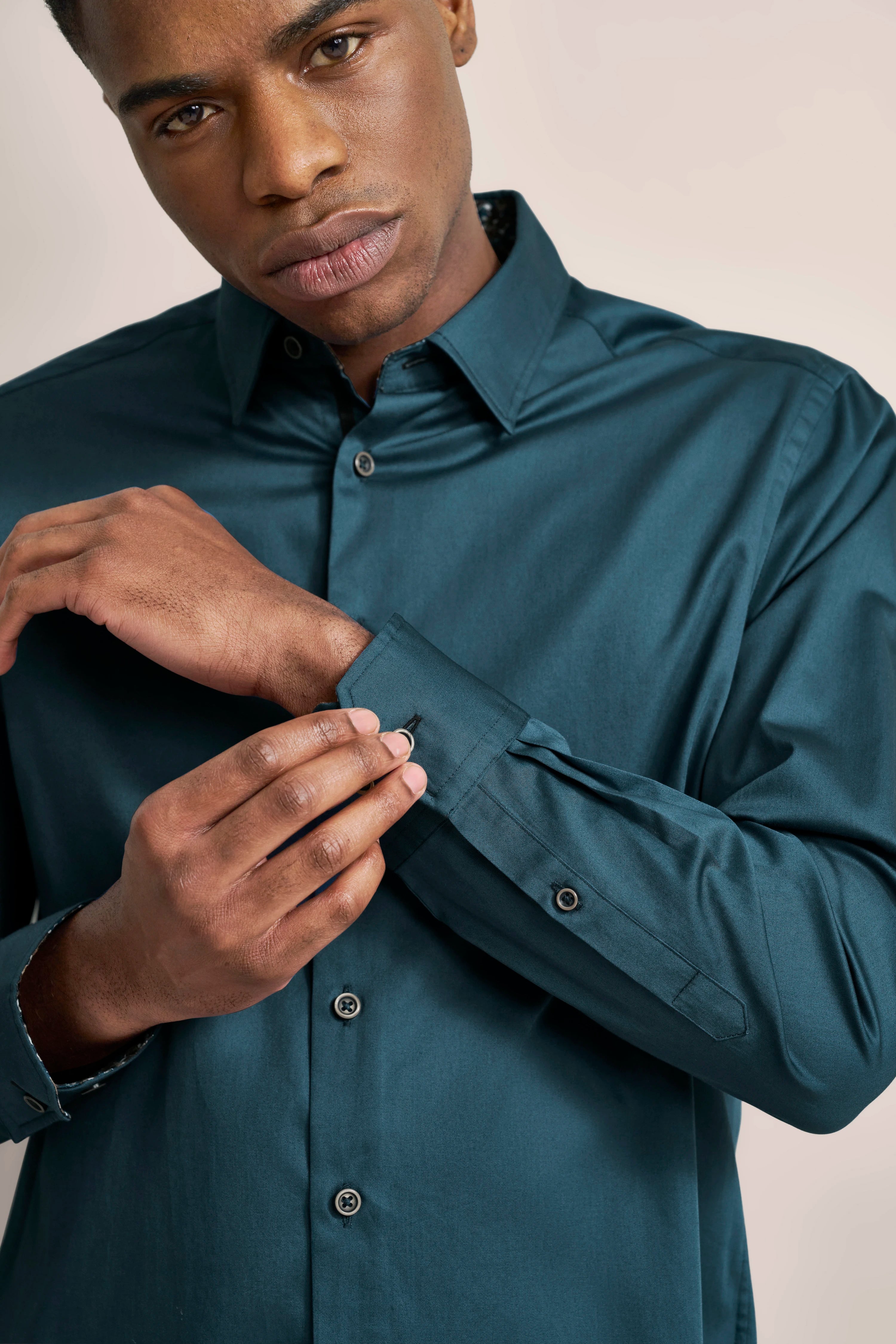 bugatti Modelbild, Posing beim Knöpfen eines dunkelgrünen Hemds.