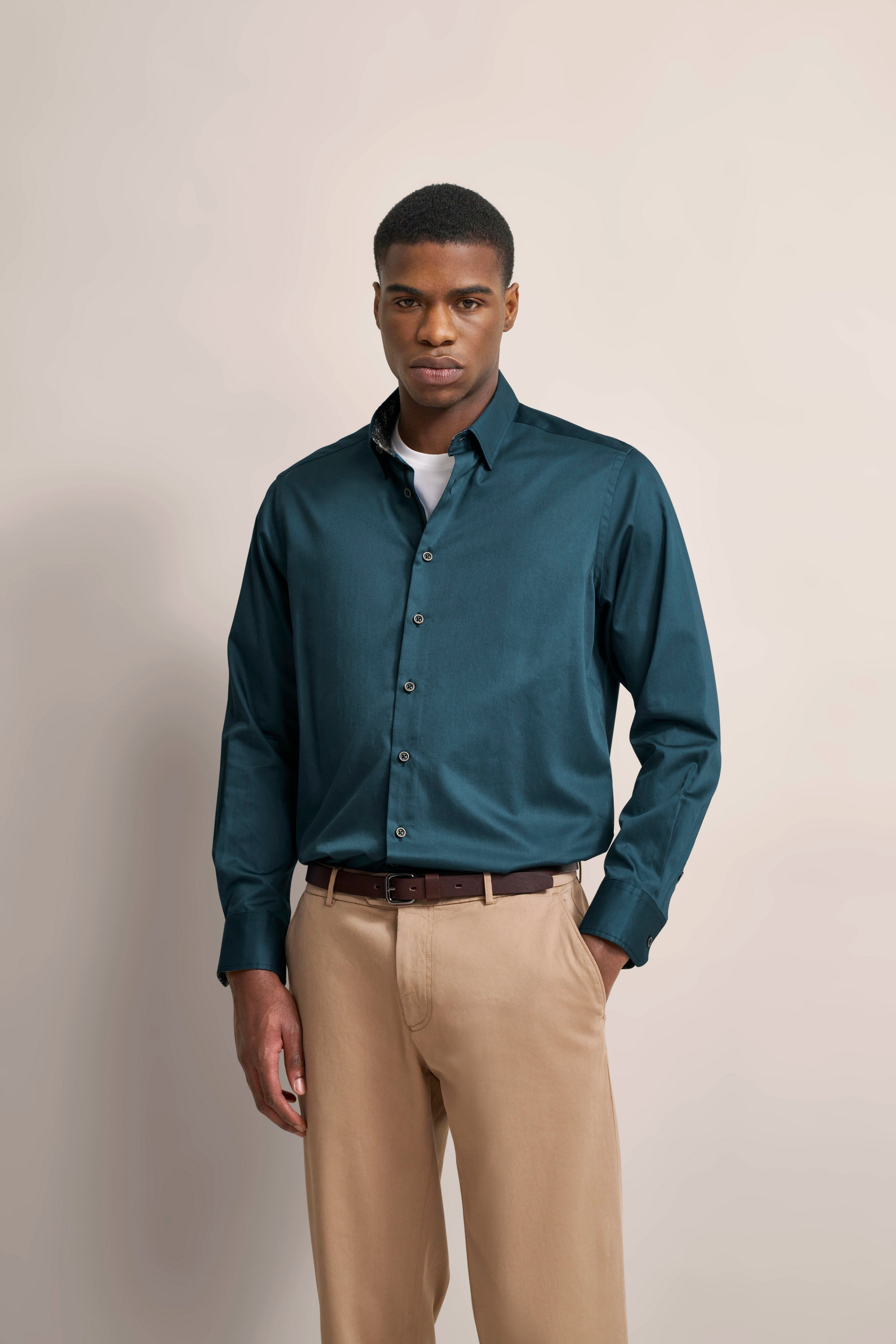 Model in grünem bugatti-Hemd und beigen Hosen, legeres Posing, entspannt und stilvoll.