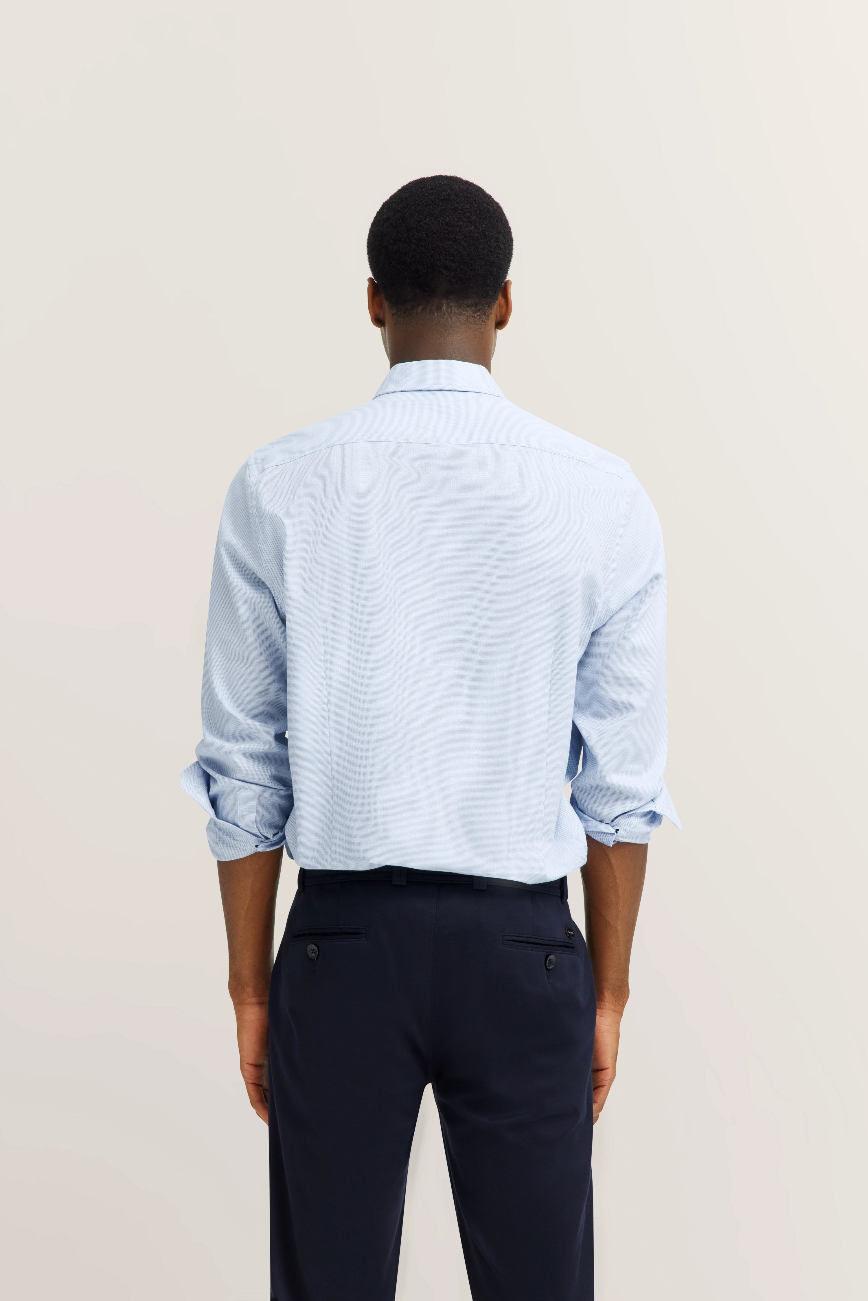 bugatti shirt in light blue, casually worn, sleeves rolled up, back view of model.