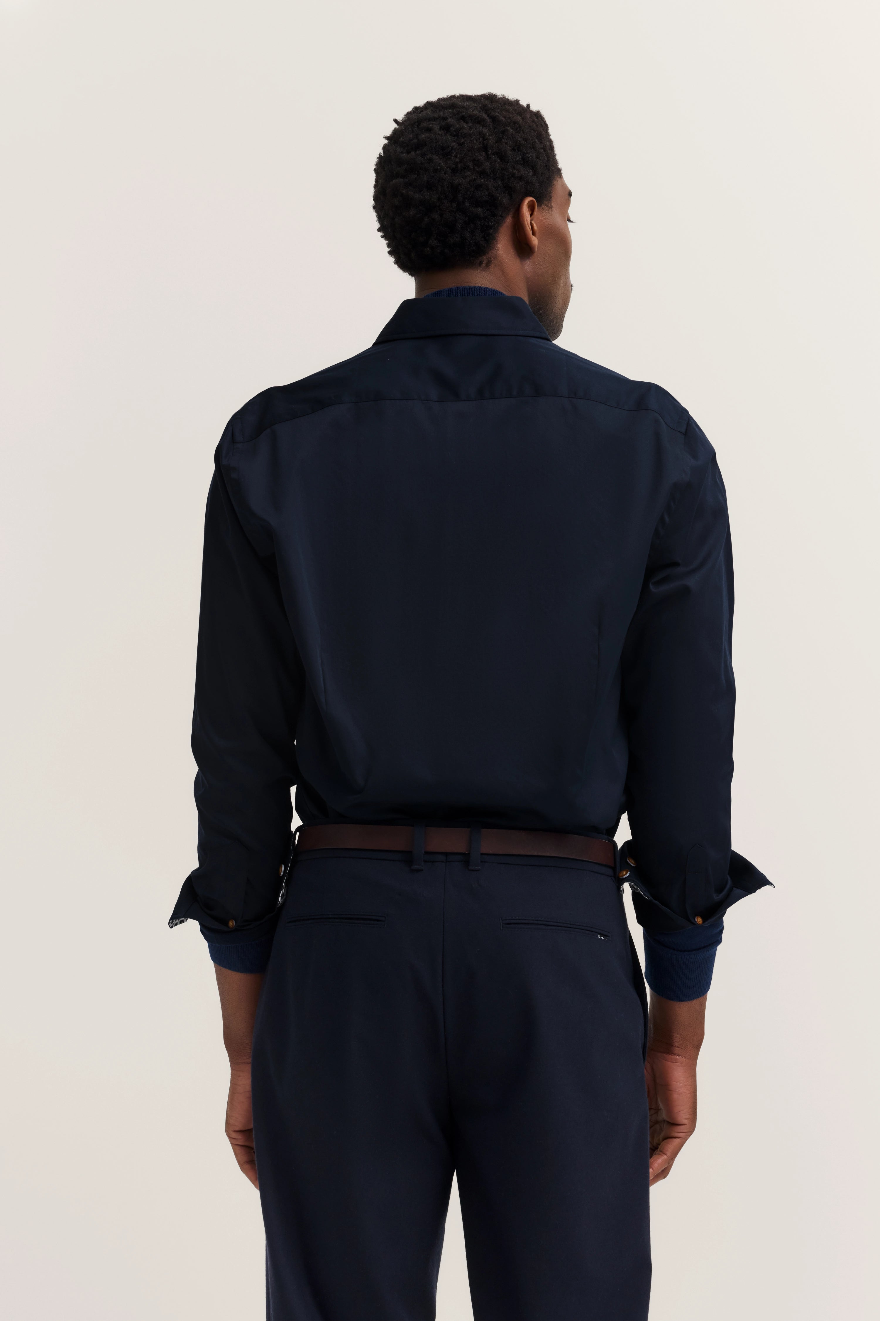Elegant model in dark blue bugatti shirt and pants from behind.