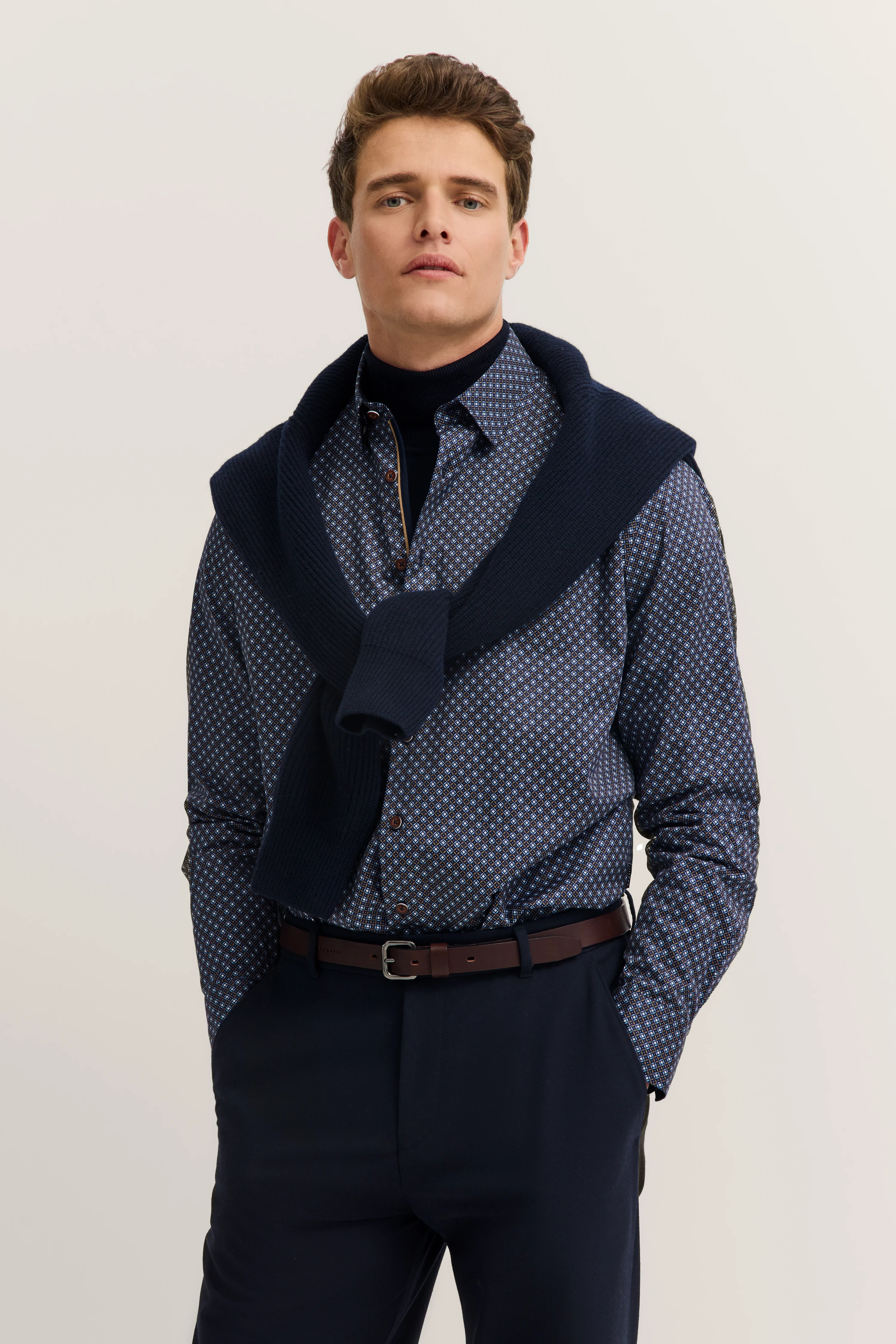 Model in patterned shirt, dark turtleneck sweater, blue pants