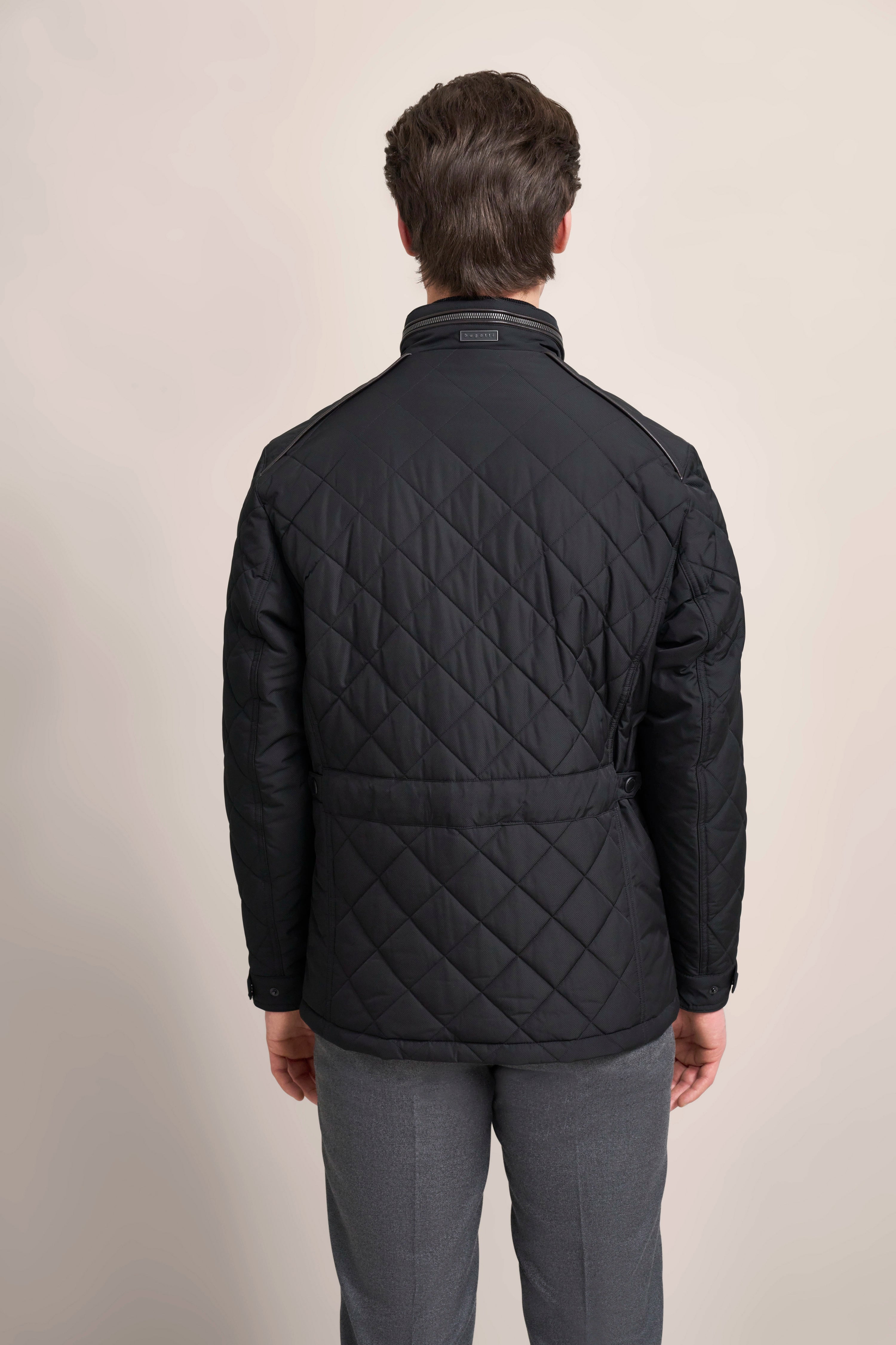 Schwarze Steppjacke von bugatti, Rückansicht, legeres Modelbild, kombiniert mit grauer Hose.