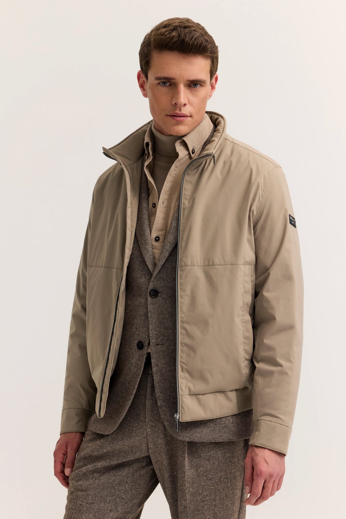 Model in beiger bugatti Jacke und braunem Anzug, elegantes Posing.