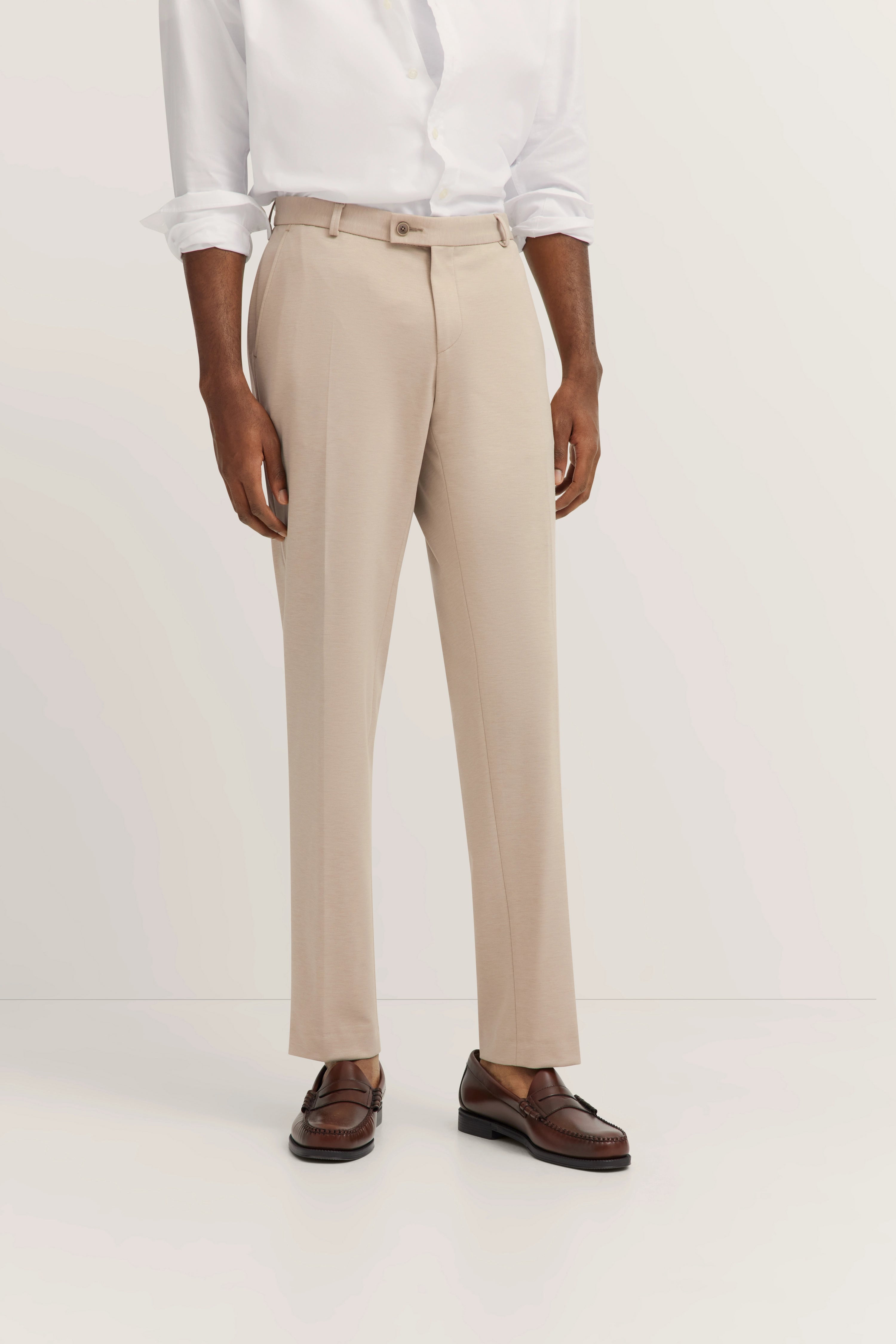 Beige Anzughose mit weißem Hemd, braune Loafers, Model stehend, bugatti Stil.