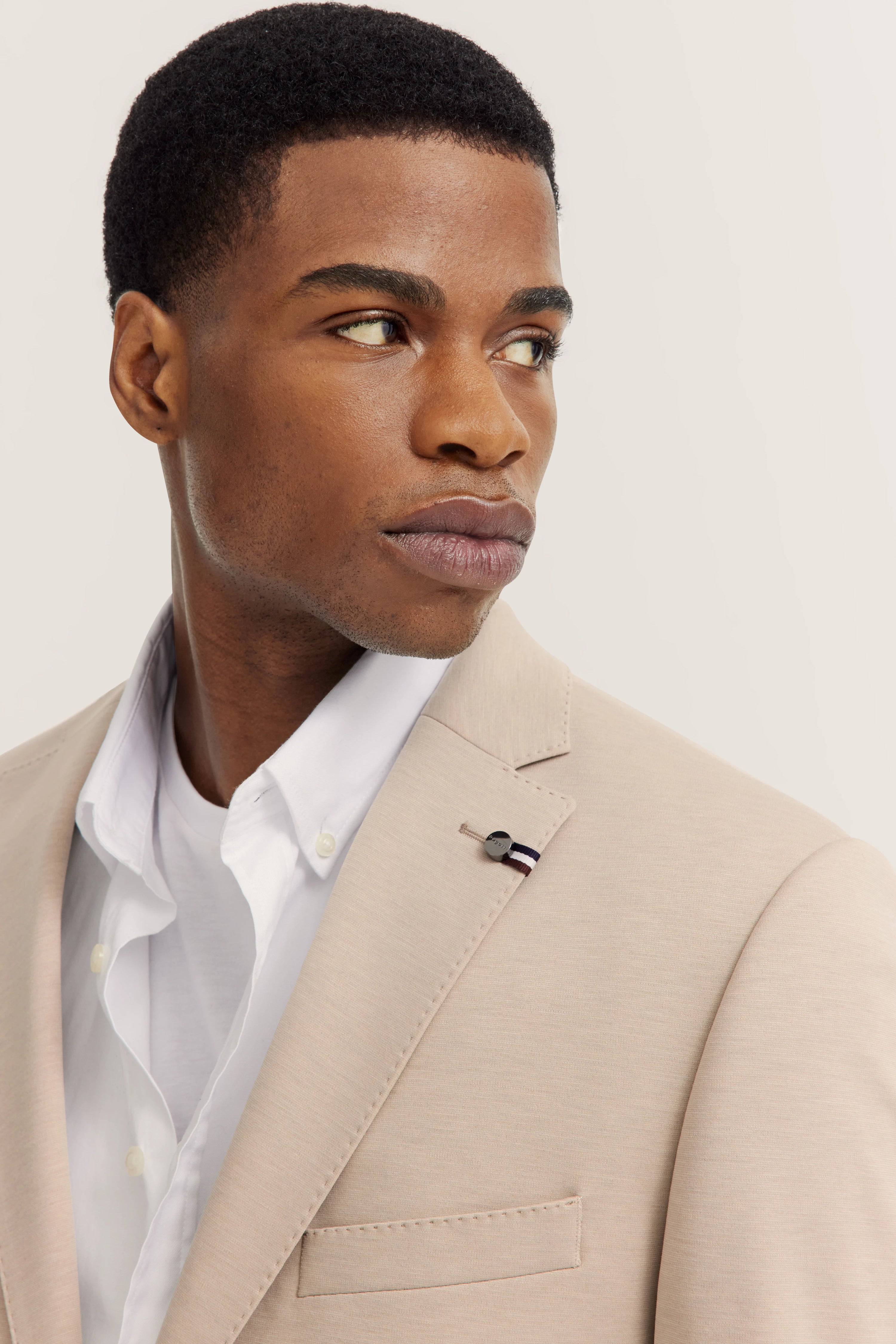 Beiger bugatti Blazer, weißes Hemd, Modelbild, Blick zur Seite, elegantes Styling.
