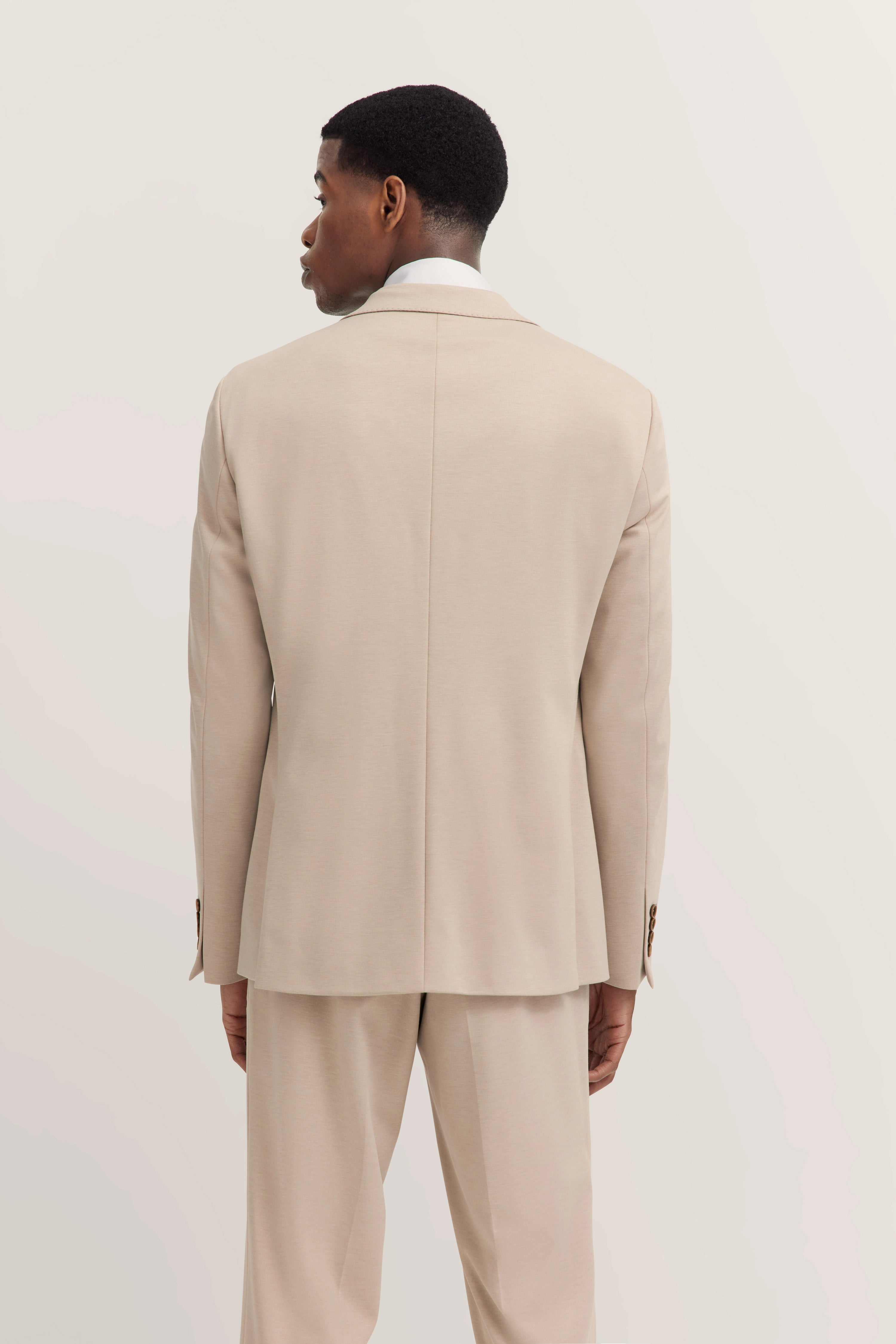 Beige bugatti Anzug von hinten, Modelbild, entspannte Haltung, stilvoll und zeitlos.