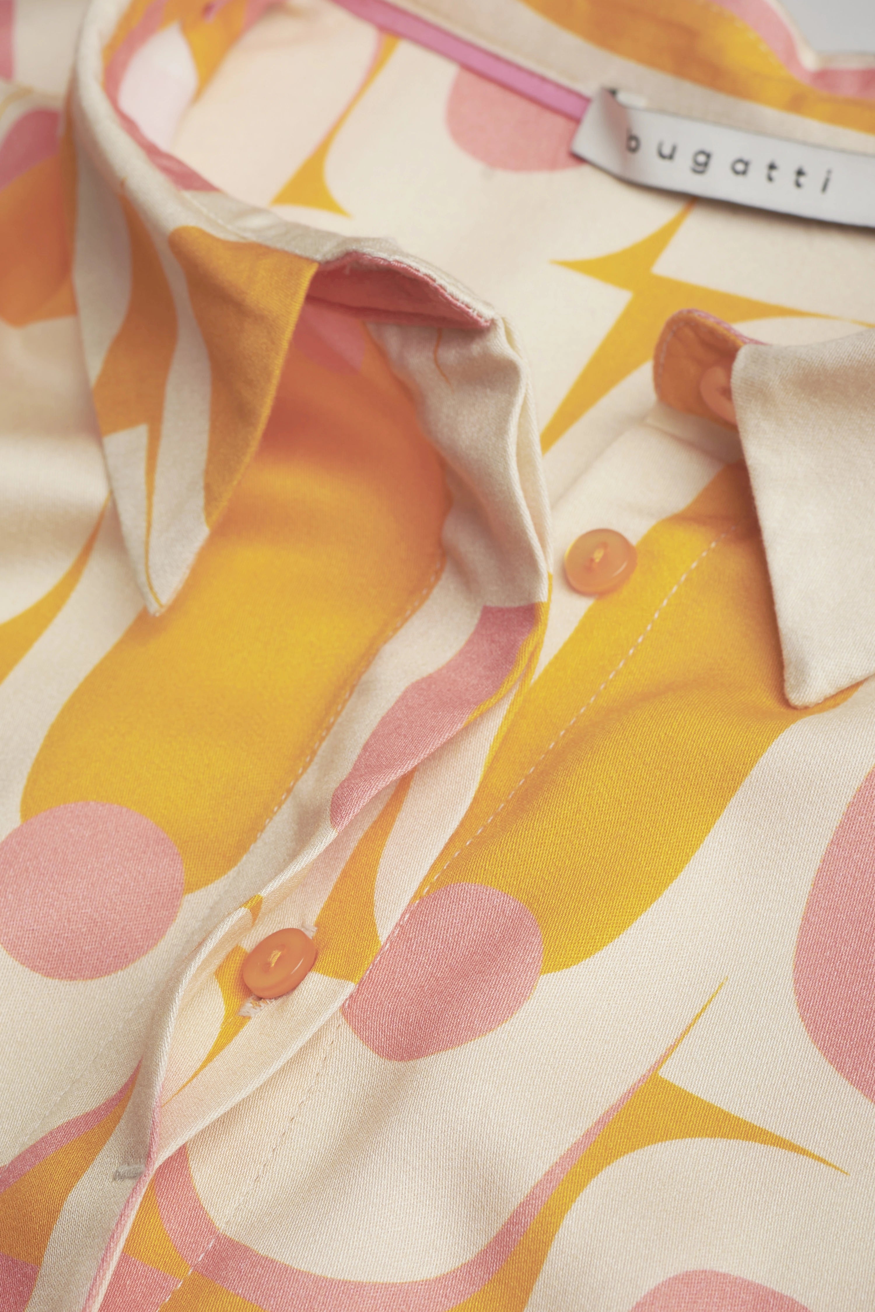 bugatti shirt in cream with yellow-pink retro pattern, close-up, elegant buttons.