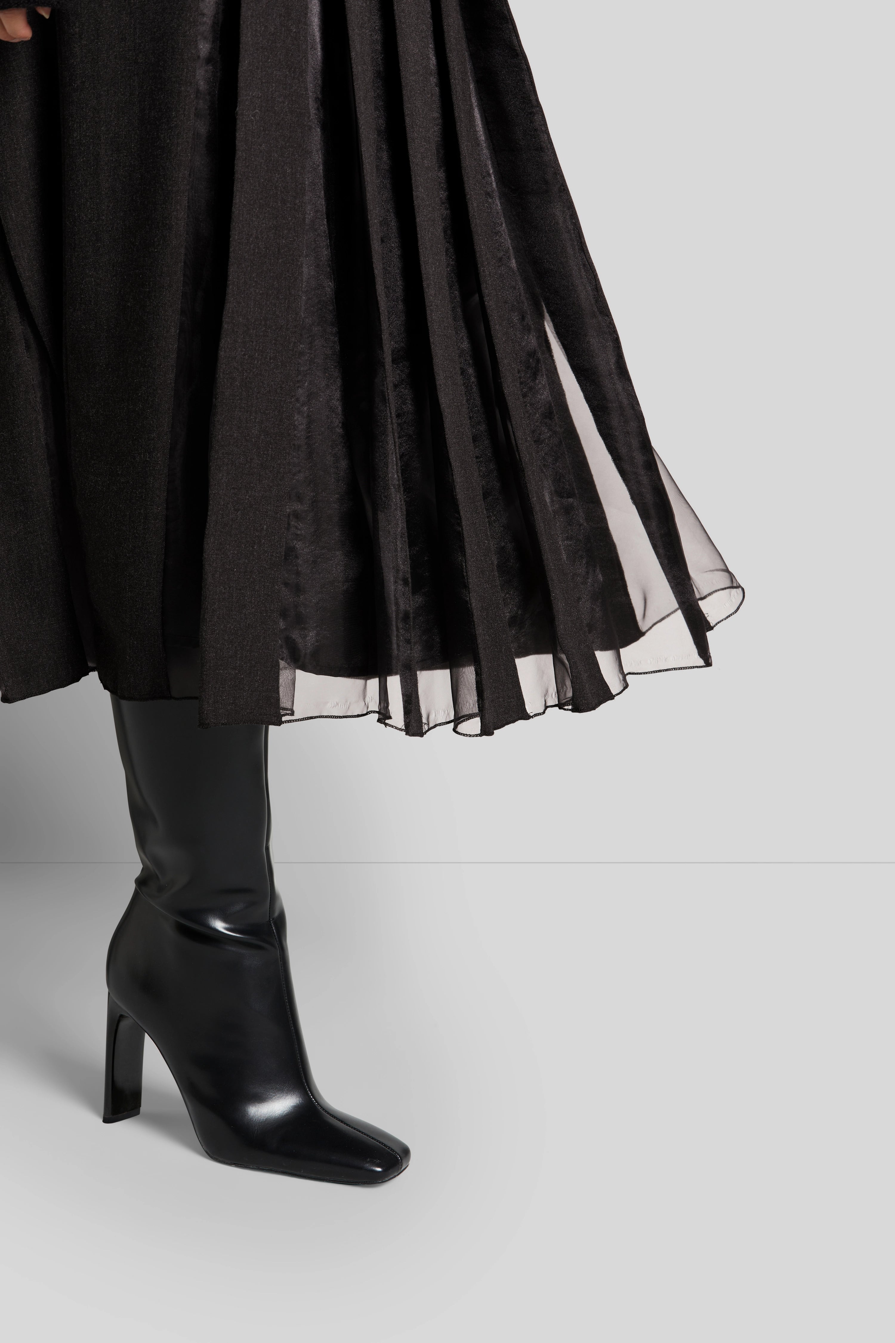 Schwarzer, fließender Rock mit schwarzen Stiefeln, Detailansicht, klassisch-elegant.