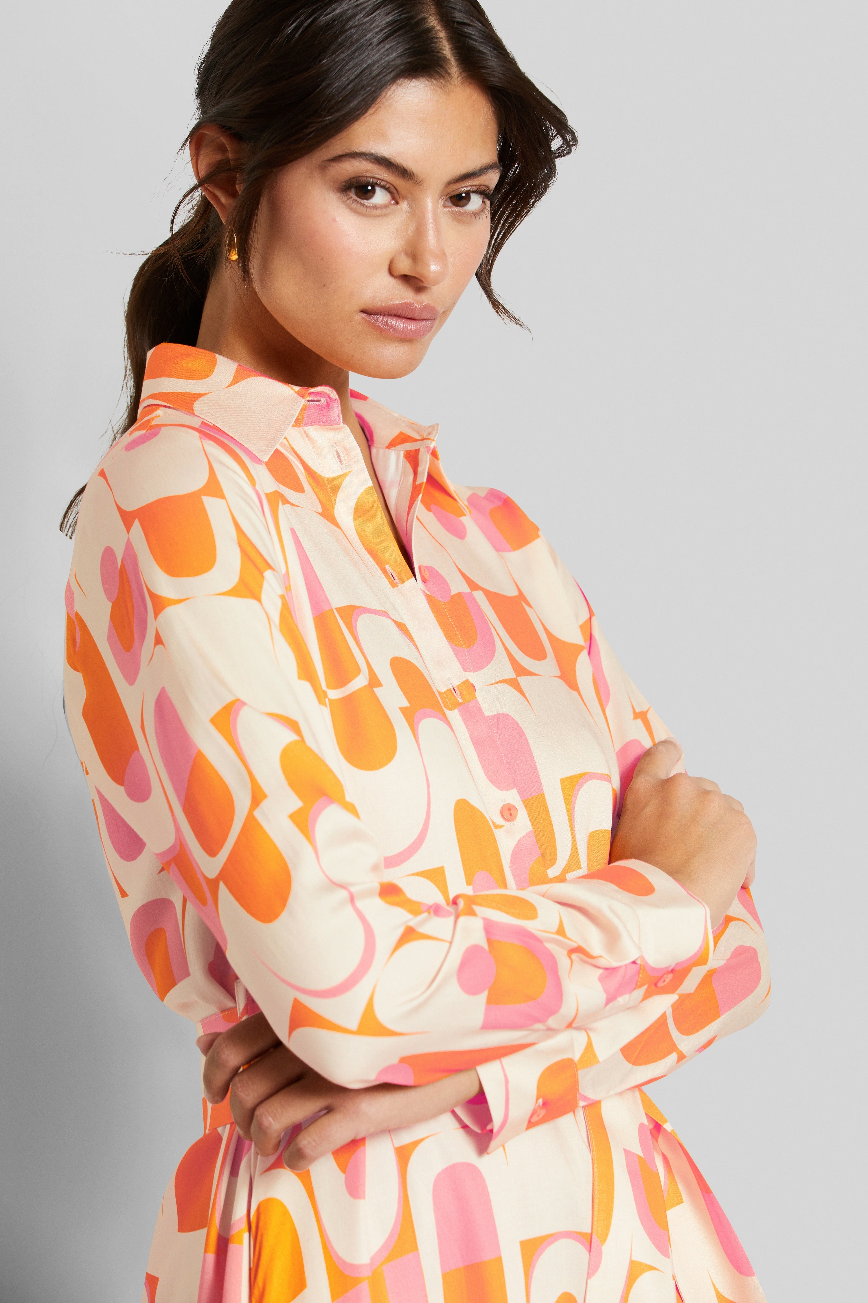 Model in patterned, colorful shirt with crossed arms, stylish and confident.
