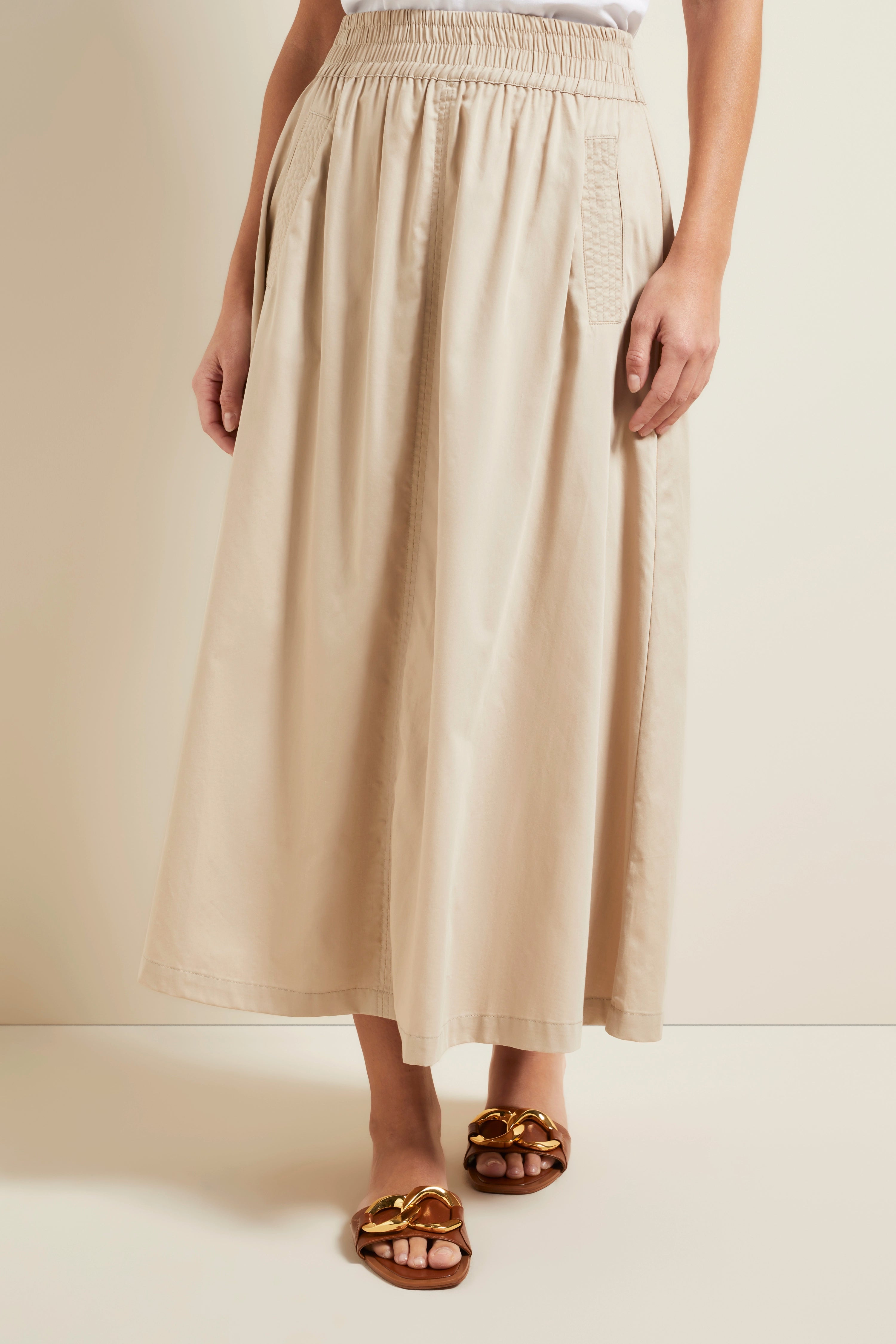 Beige maxi skirt with elastic waistband, styled casually, paired with brown sandals.