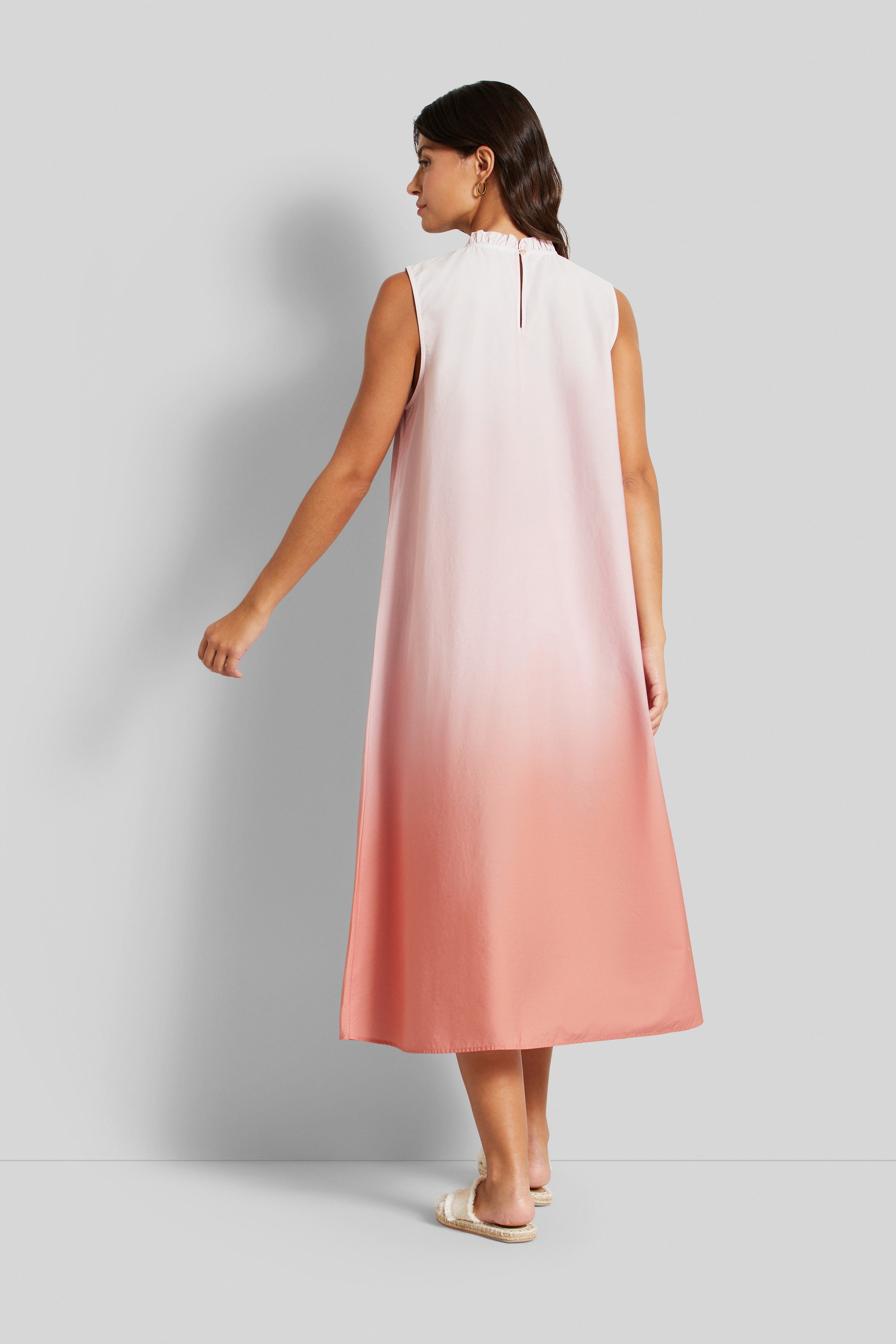 Ärmelloses Ombre-Kleid in Rosa und Lachs, Model im Profil, entspannte Pose.