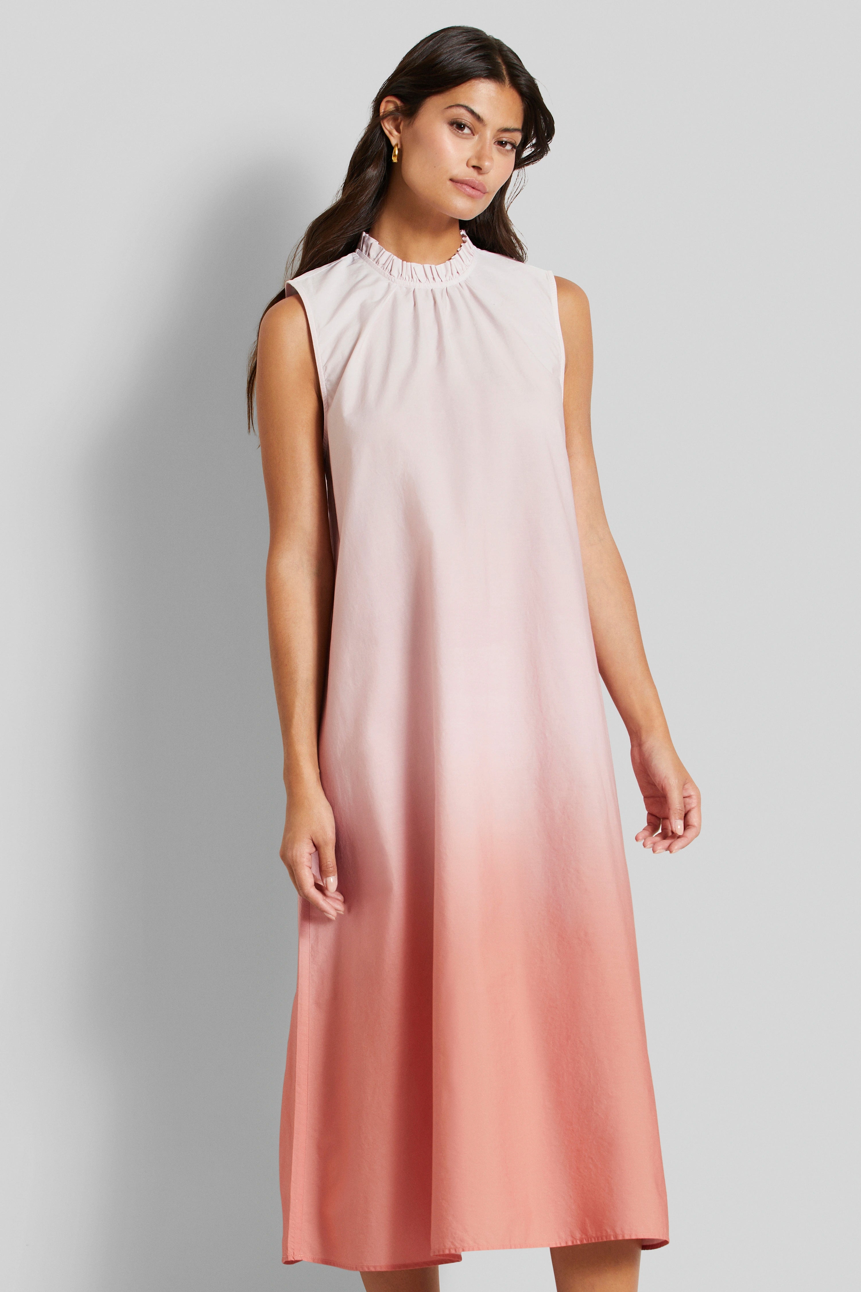 Ärmelloses Kleid in Rosa- und Koralltönen, Modelbild, entspanntes Stehen, bugatti Stil und Eleganz.