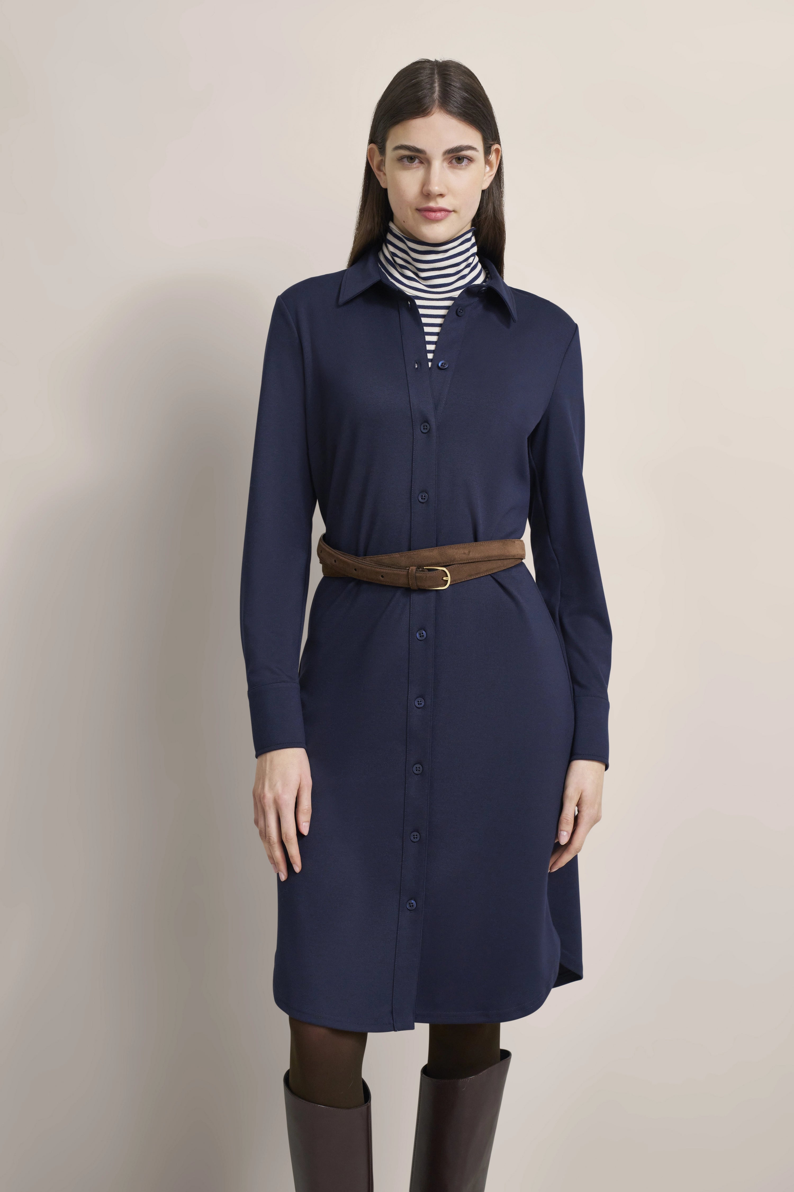 Women's outfit: Blue shirt dress, striped turtleneck, brown belt. Model standing, hands relaxed.