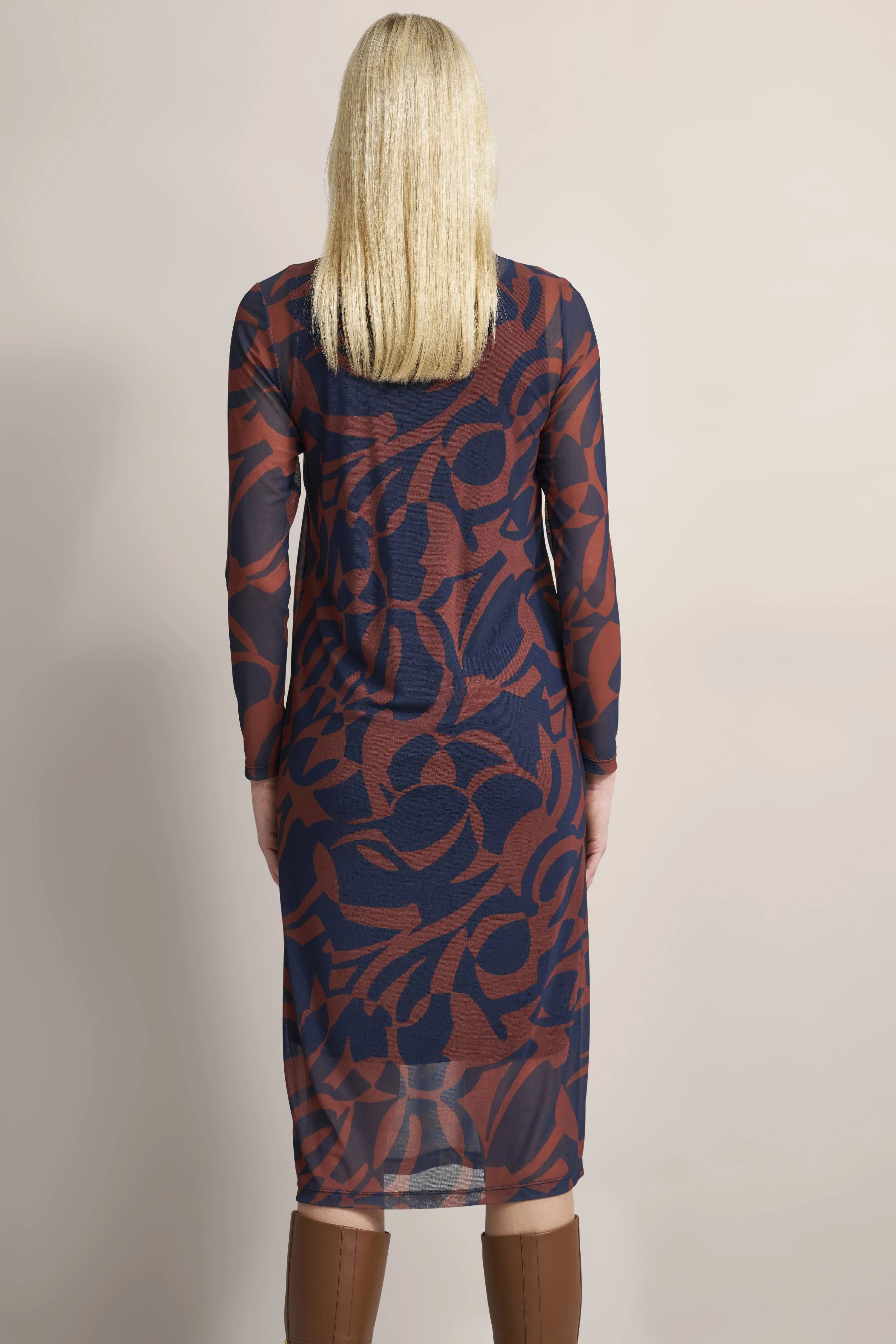 Langes Kleid mit abstraktem Muster in Braun und Blau, Model von hinten, trägt braune Stiefel.