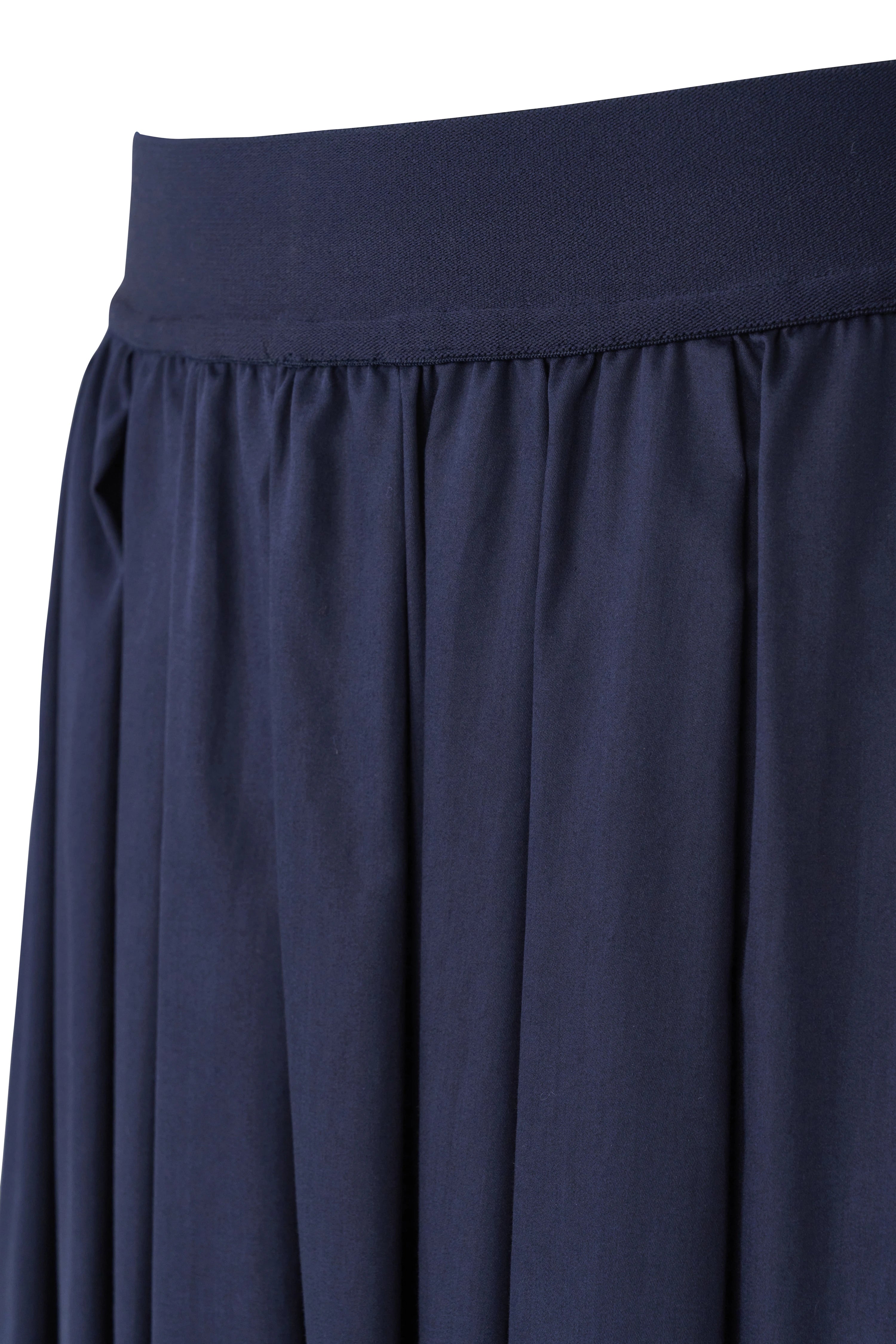 Donkerblauwe rok van vloeiende stof, close-up, casual beeld, detailweergave met hand in zak.