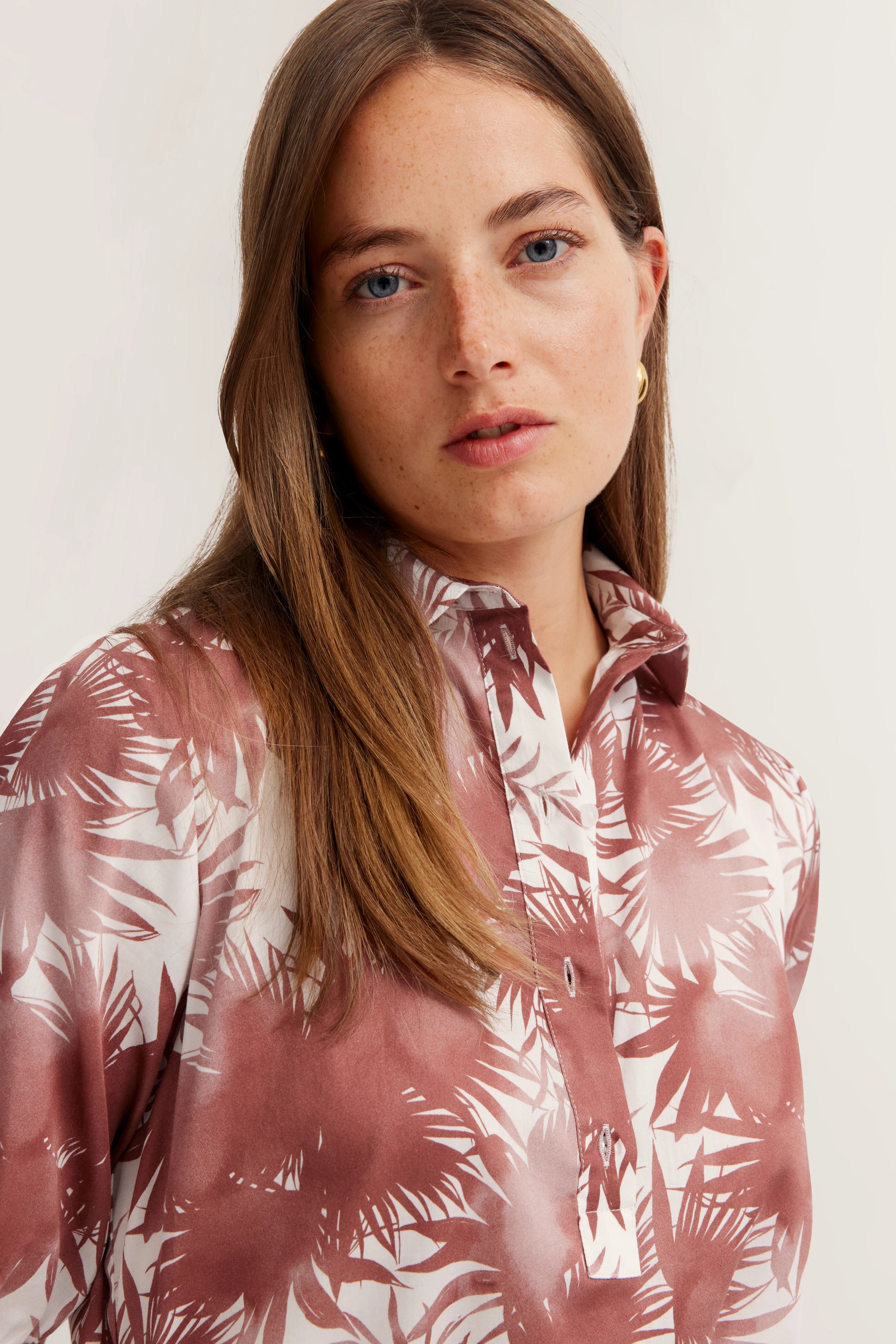 Damesportret: vrouw in bugatti blouse met bruin-wit palmprint, ontspannen pose.