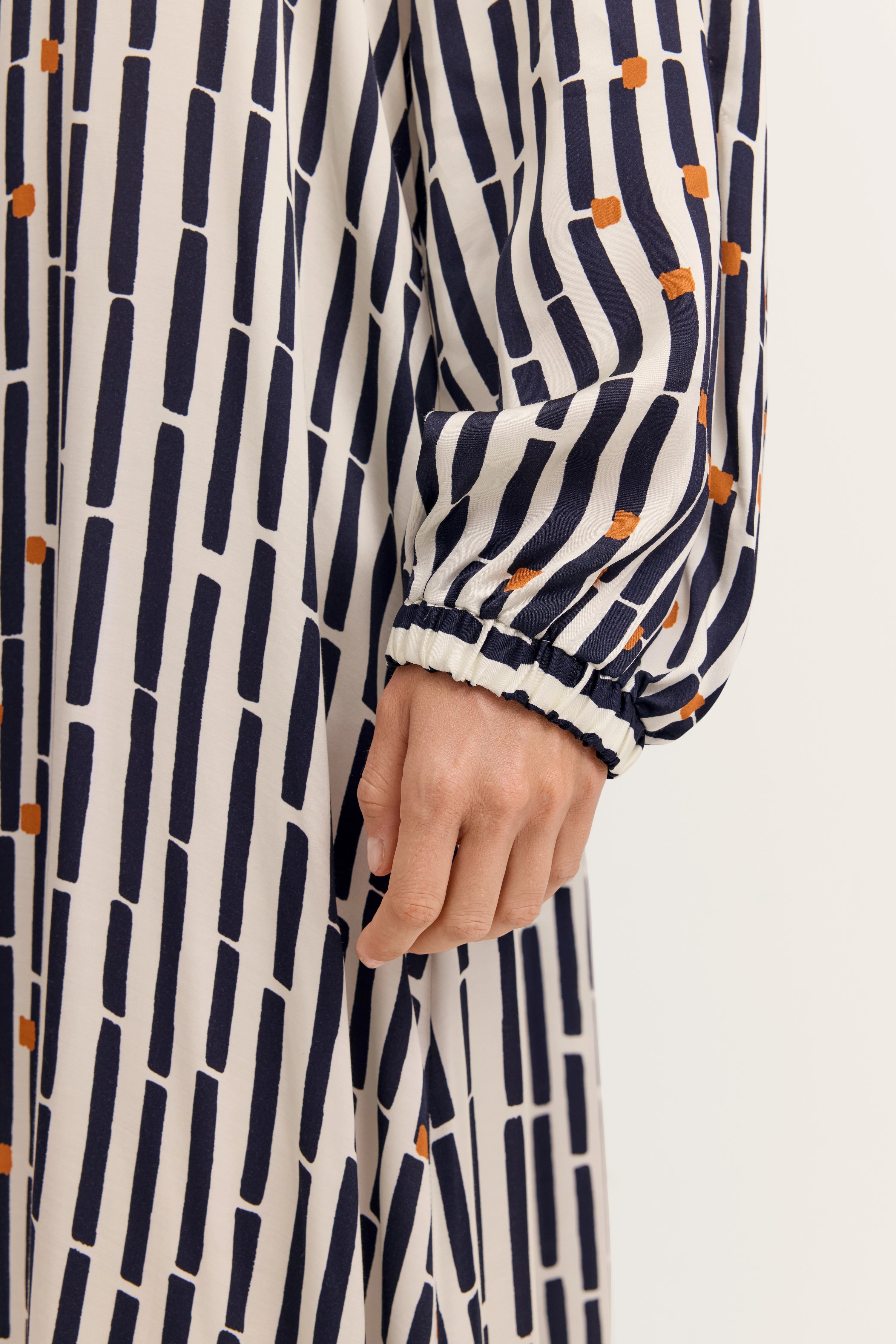 Langerärmel-Kleid im grafischen Muster in Dunkelblau und Weiß mit orangefarbenen Akzenten, Detailansicht.