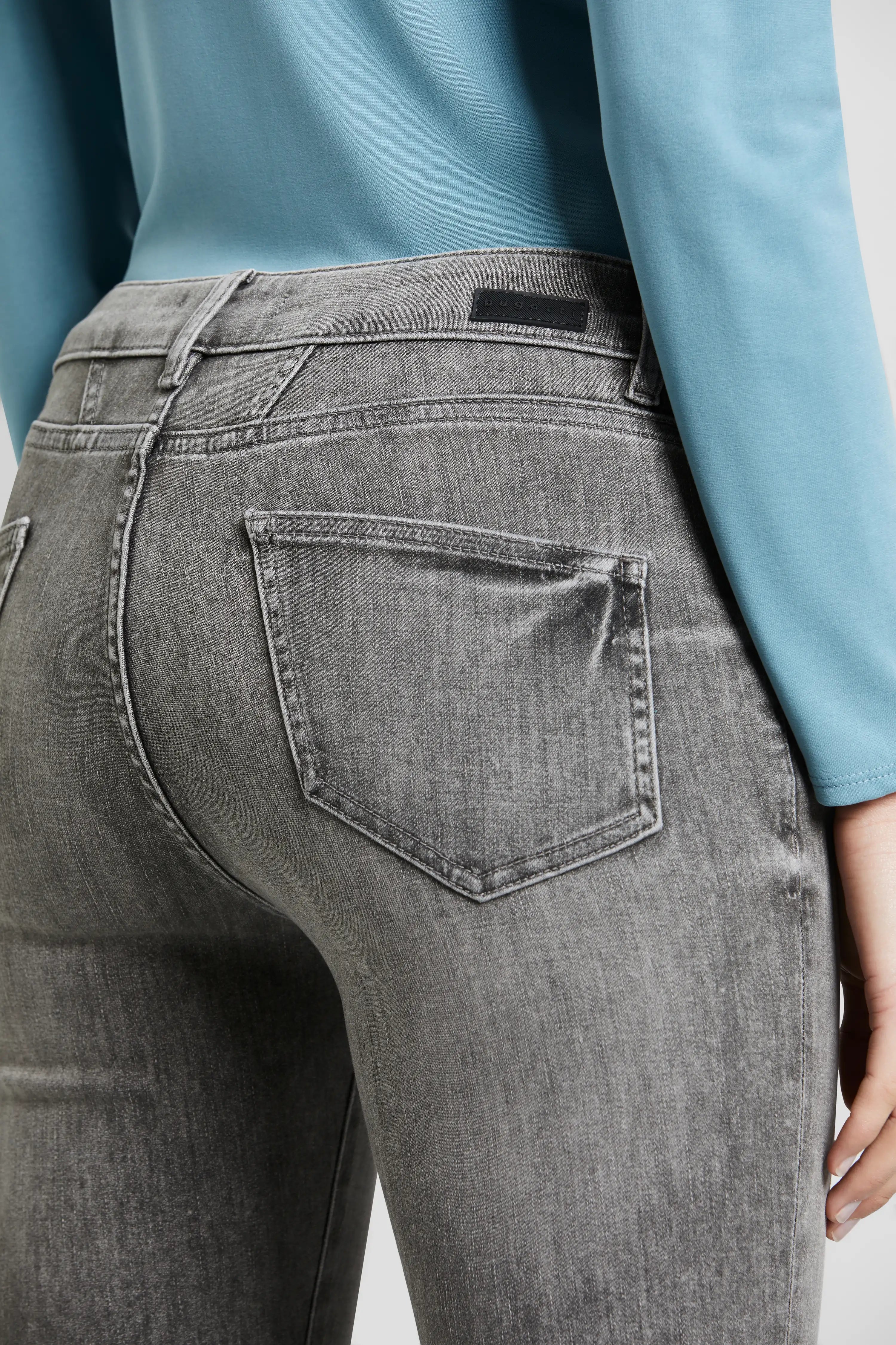 Graue Jeans von bugatti, Büstenbild, kombiniert mit einem hellblauen Oberteil, dezent stilvoll.