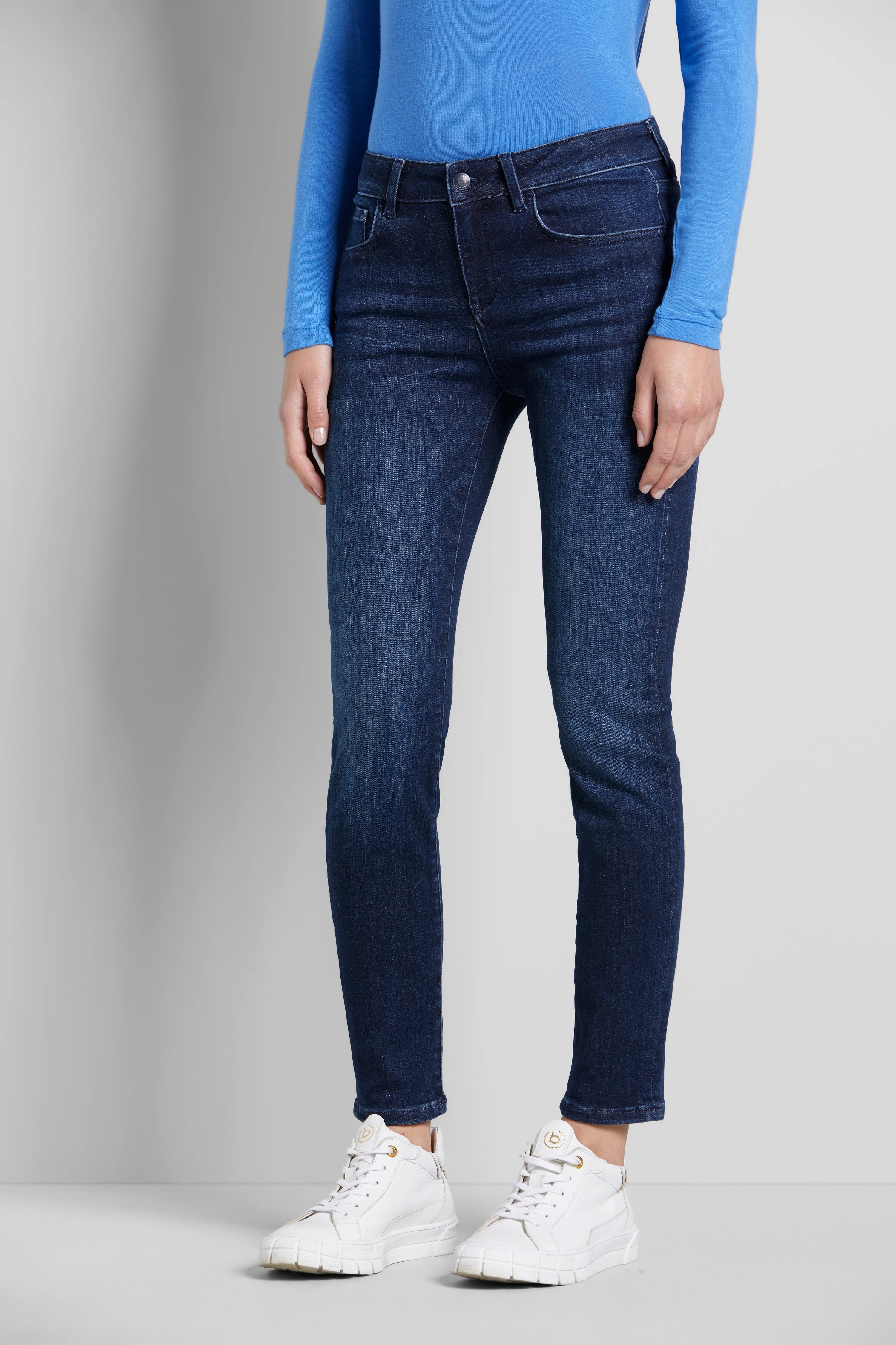 Blaues Top, dunkelblaue Jeans, weiße Sneaker