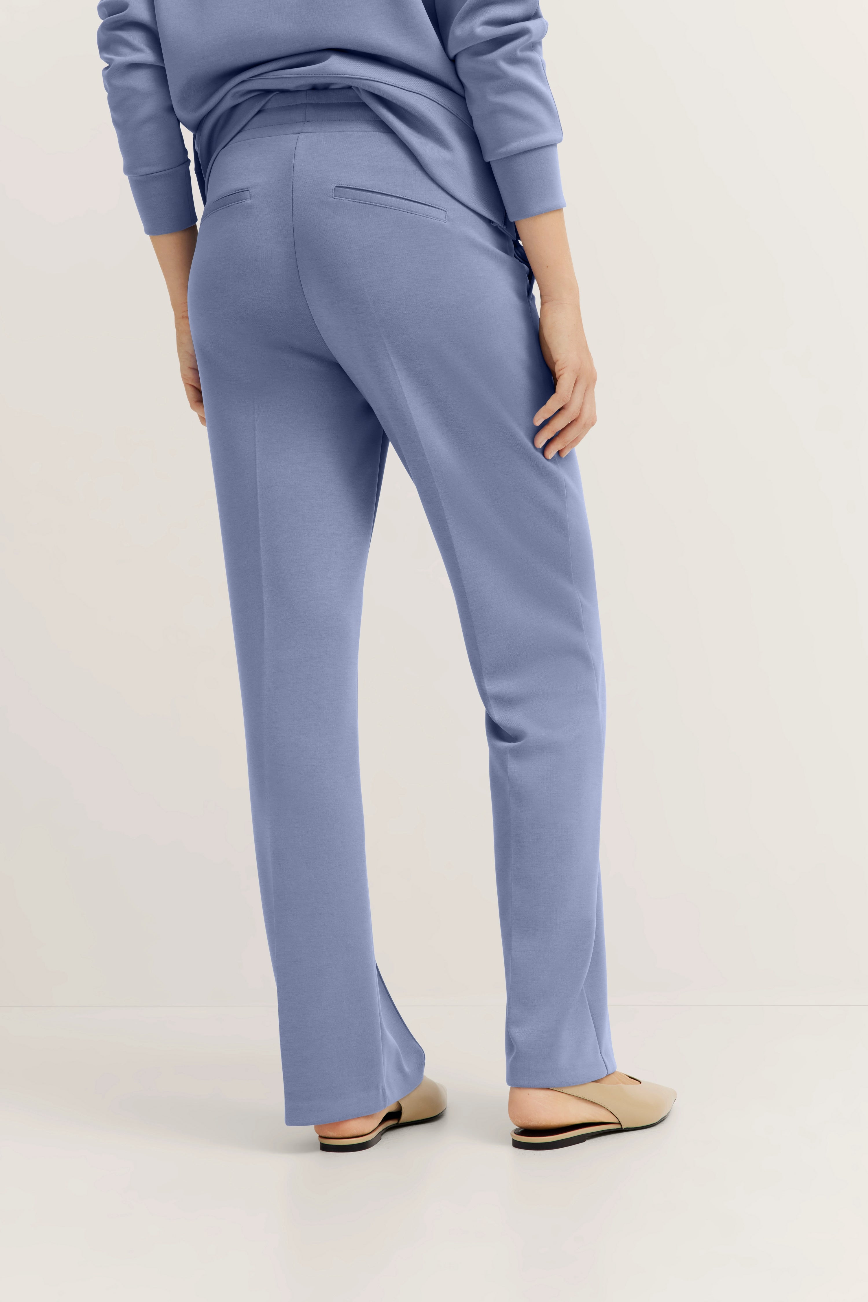 Woman in blue bugatti pants, casual pose, beige shoes.
