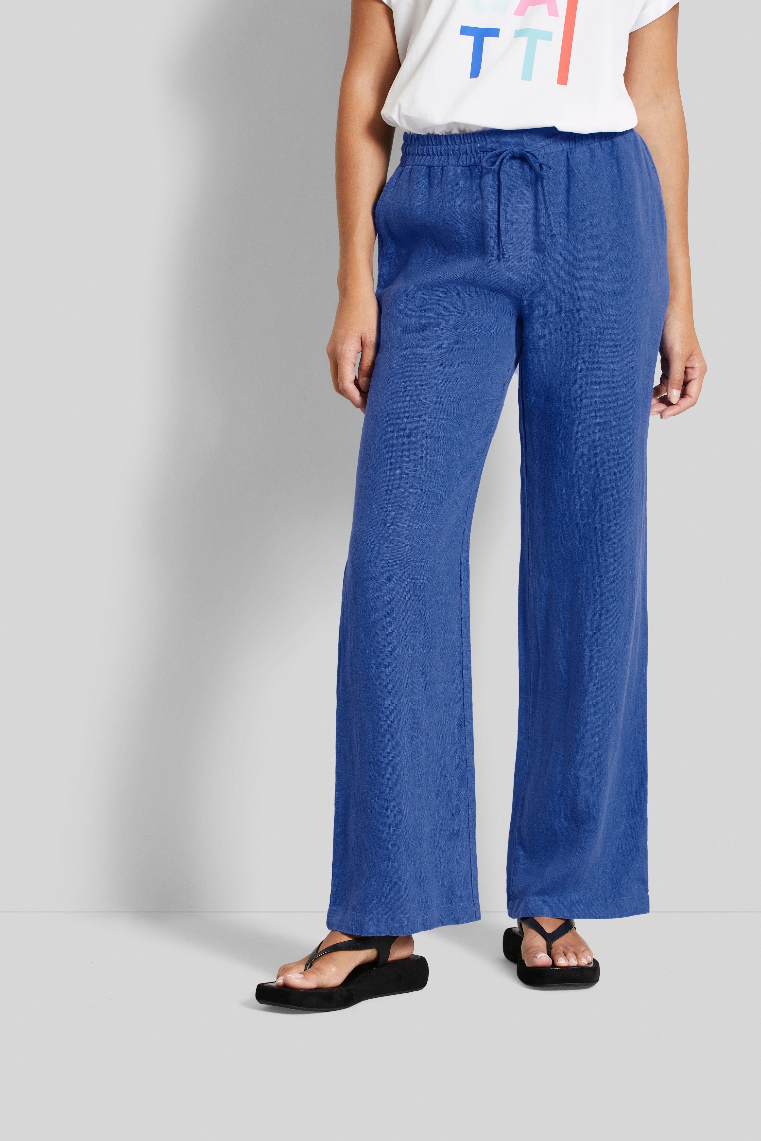 Weißes T-Shirt mit Print, blaue weite Hose, schwarzer Sandale