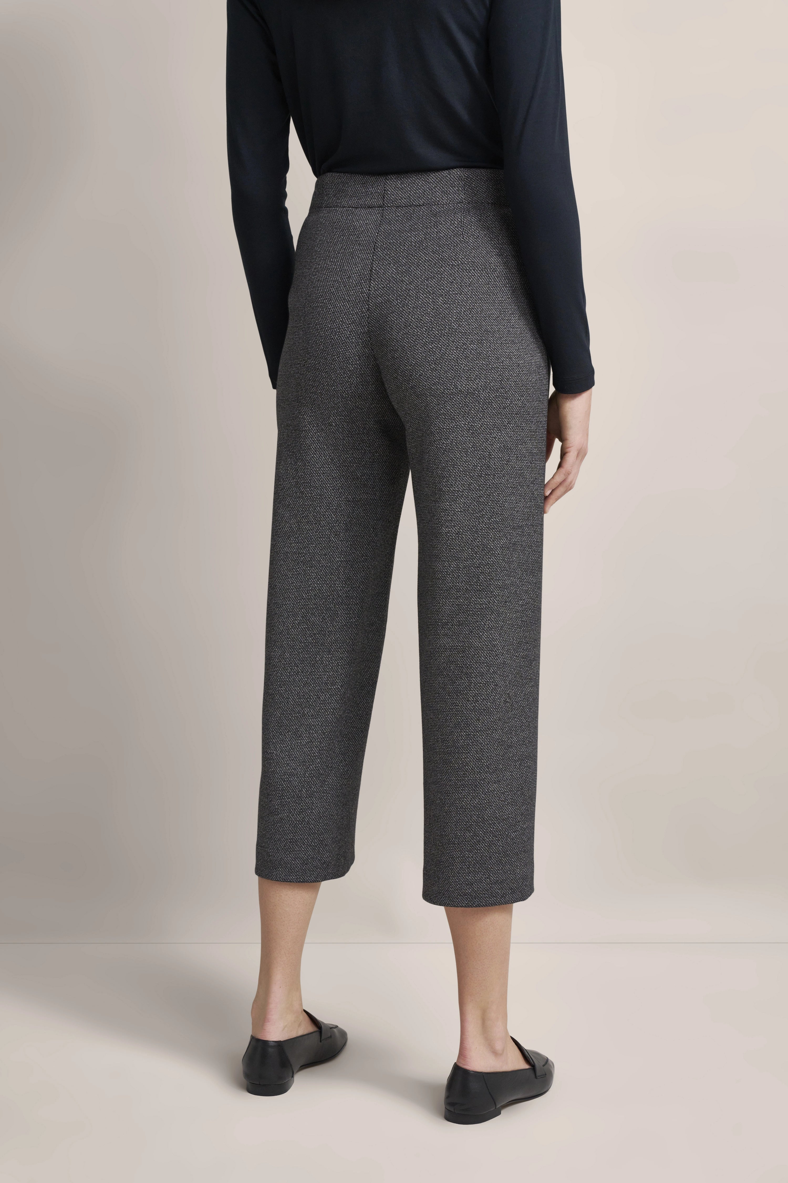 Graue, gemusterte Hose, schwarzes Oberteil, Büstenbild, eleganter, stilvoller Look von bugatti.