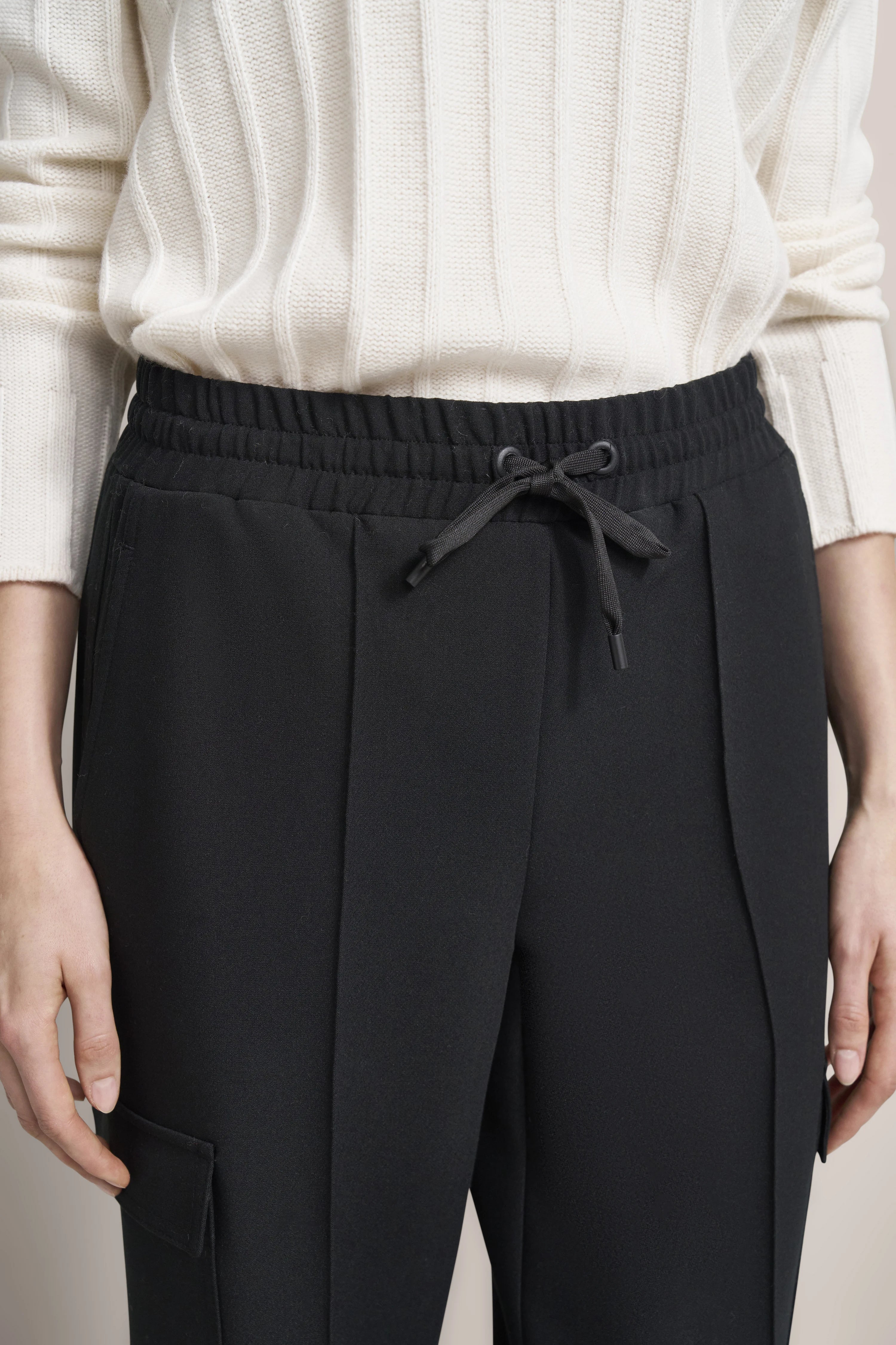 Weißer Pullover und schwarze Jogginghose, Detailaufnahme, legerer Stil, bugatti Eleganz und Komfort.