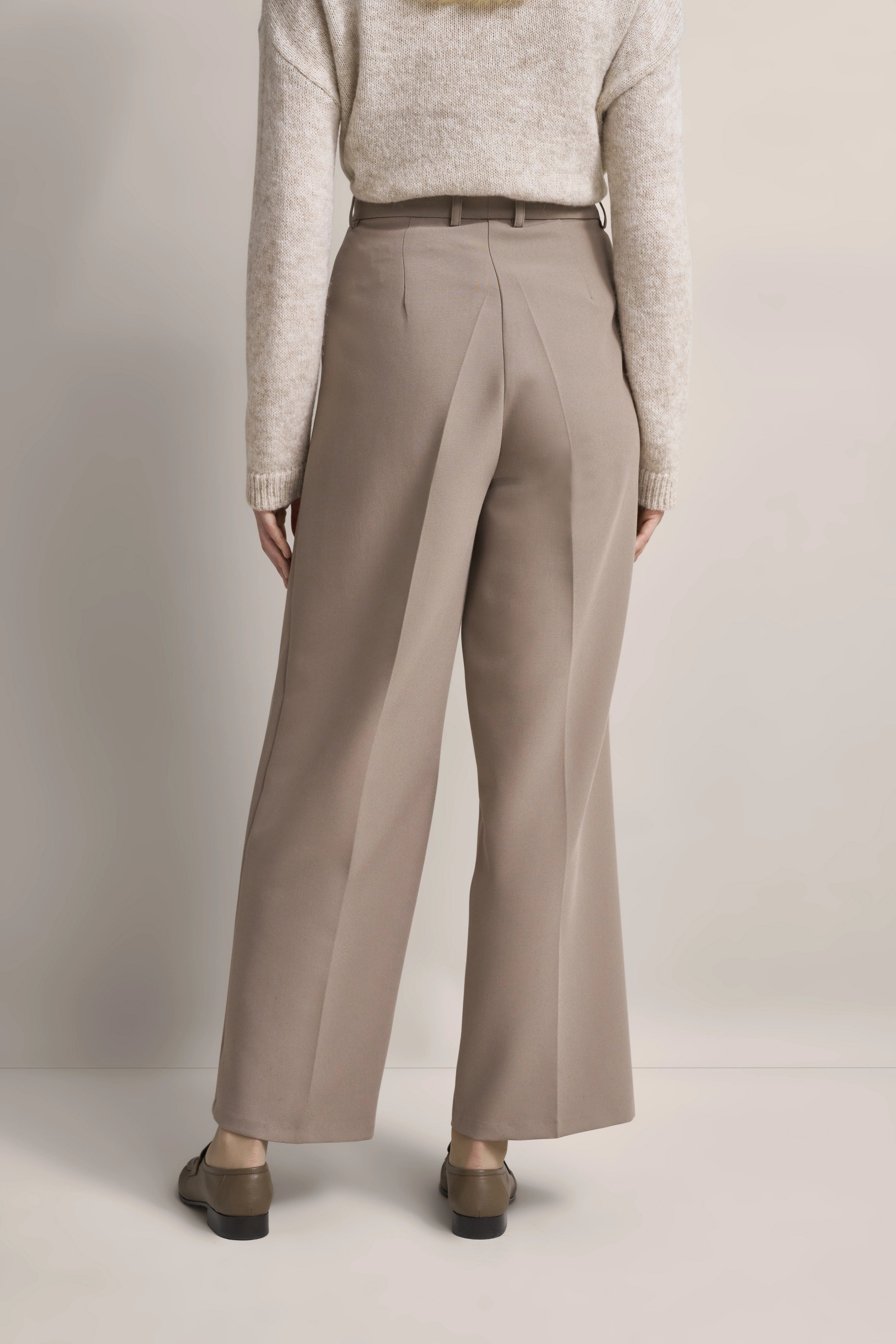 Beiger Pullover mit cremefarbenen Hosen, legeres Modelbild von hinten, stilvoll und elegant.