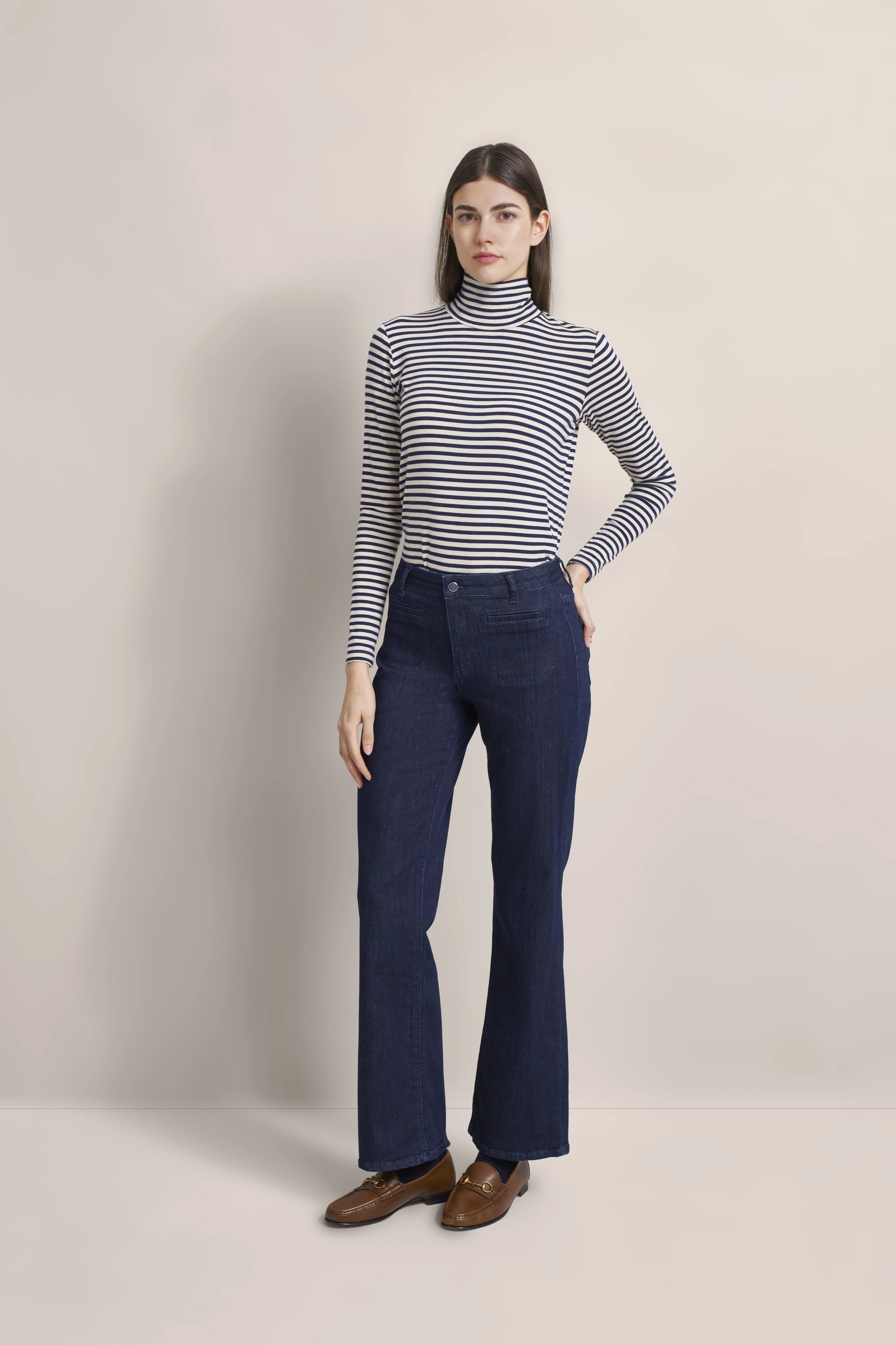 Model in gestreiftem Rollkragenpullover und dunkelblauer Hose, entspanntes Posing, bugatti Stil.