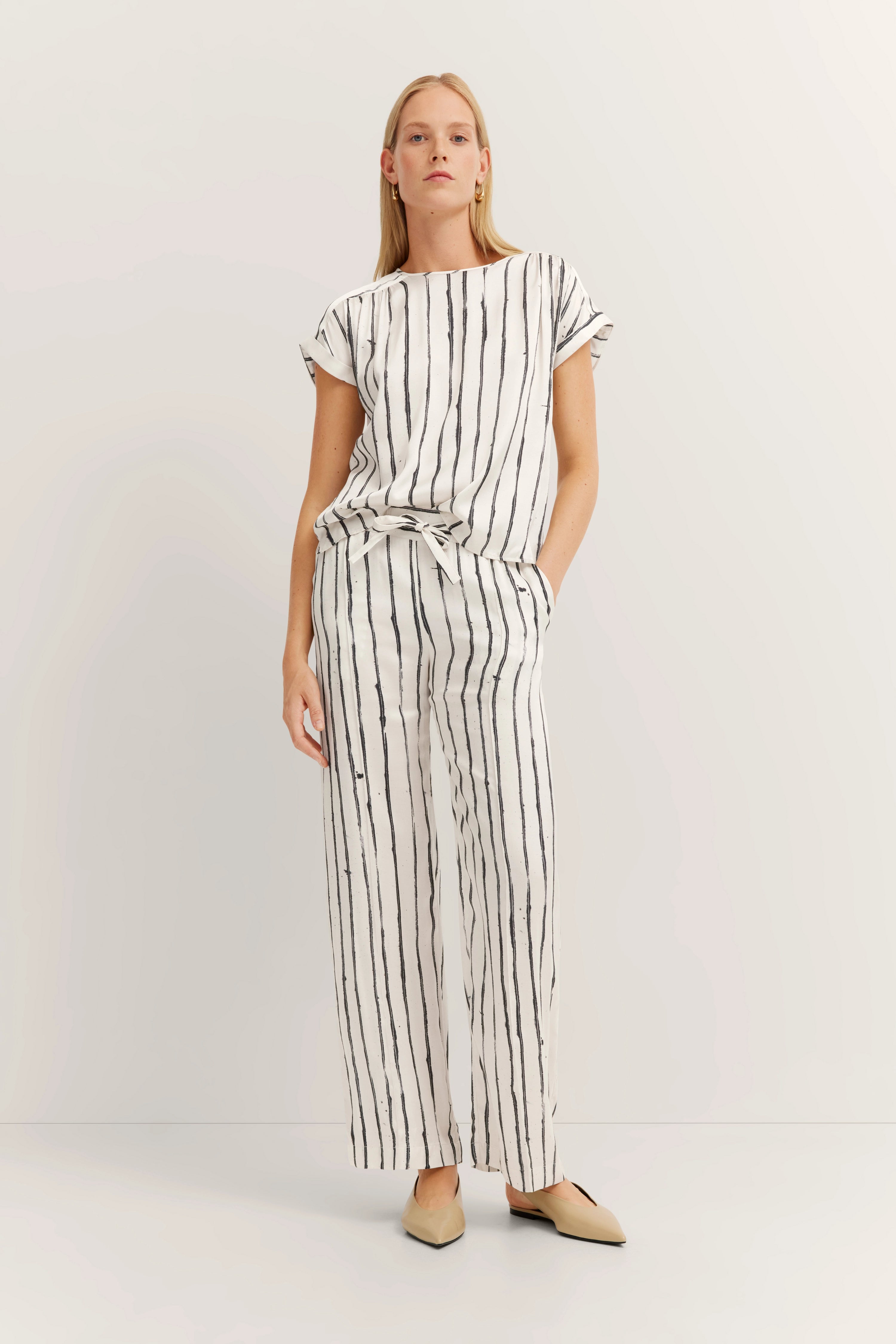 Striped set in white with black stripes, model stands relaxed with hands in pockets. Bugatti elegance and style.