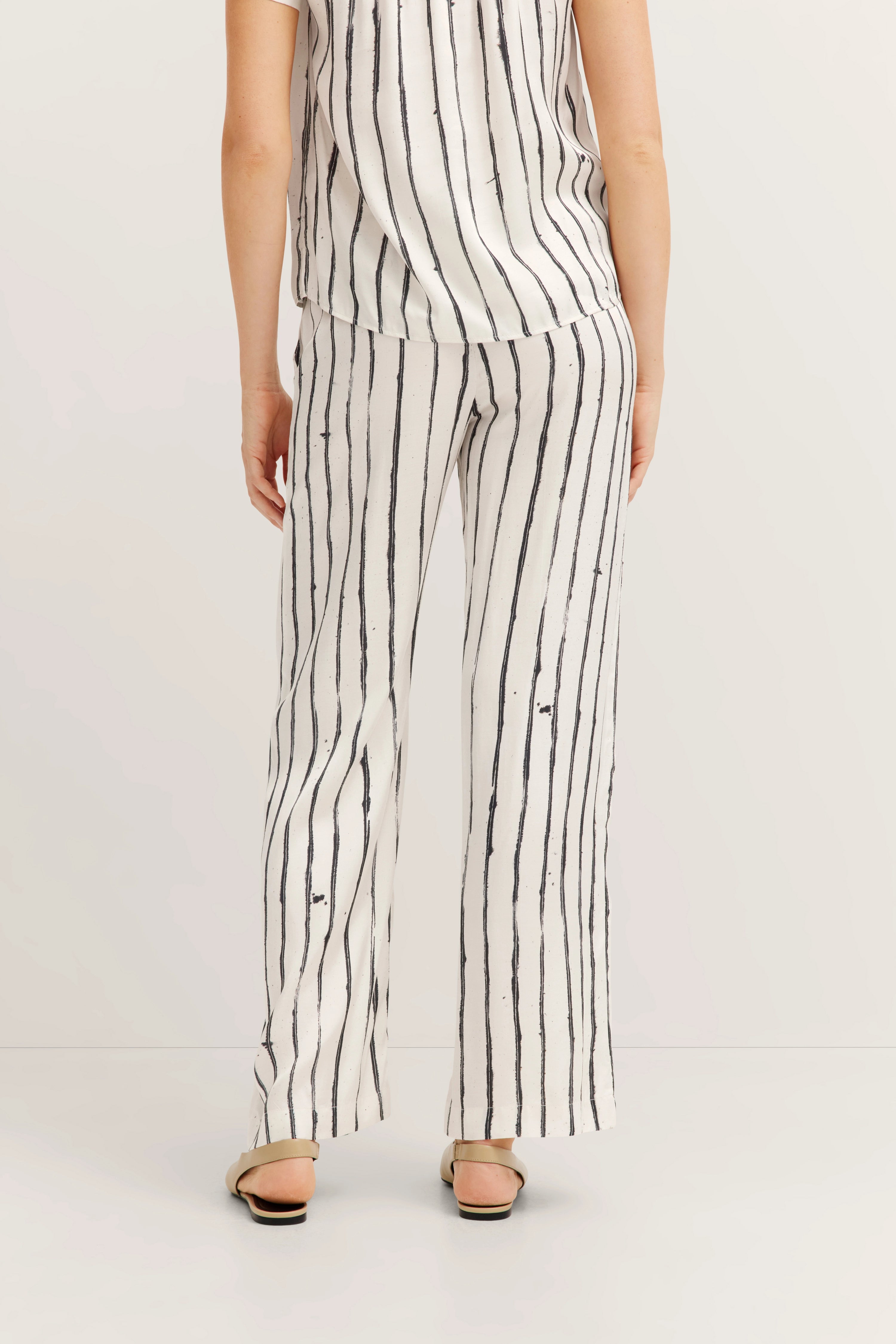 White striped bugatti outfit, top and pants. Casual model image, rear view.