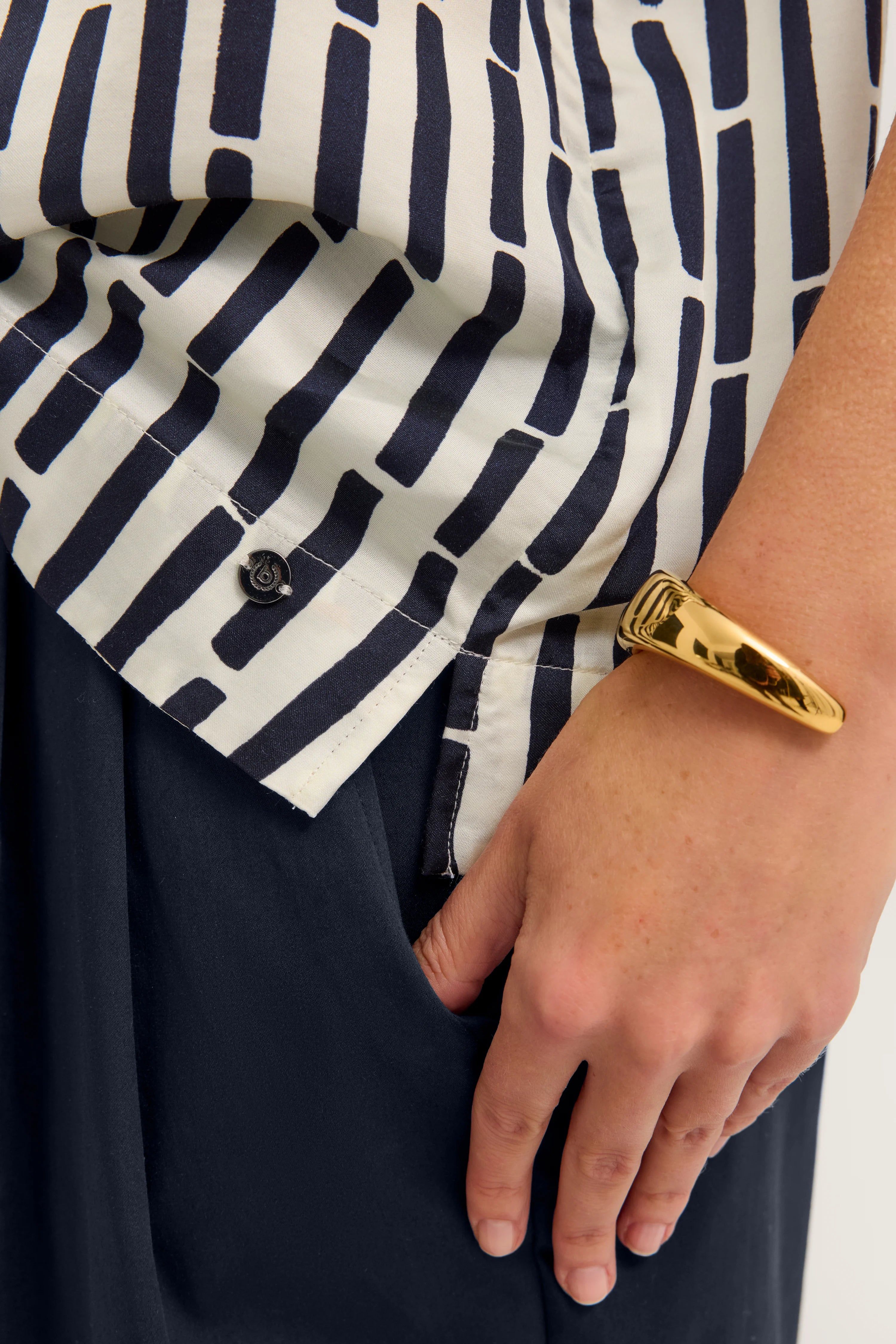 Streifenbluse in Navy und Weiß, Büstenbild, Hand mit goldenem Armreif in der Tasche.