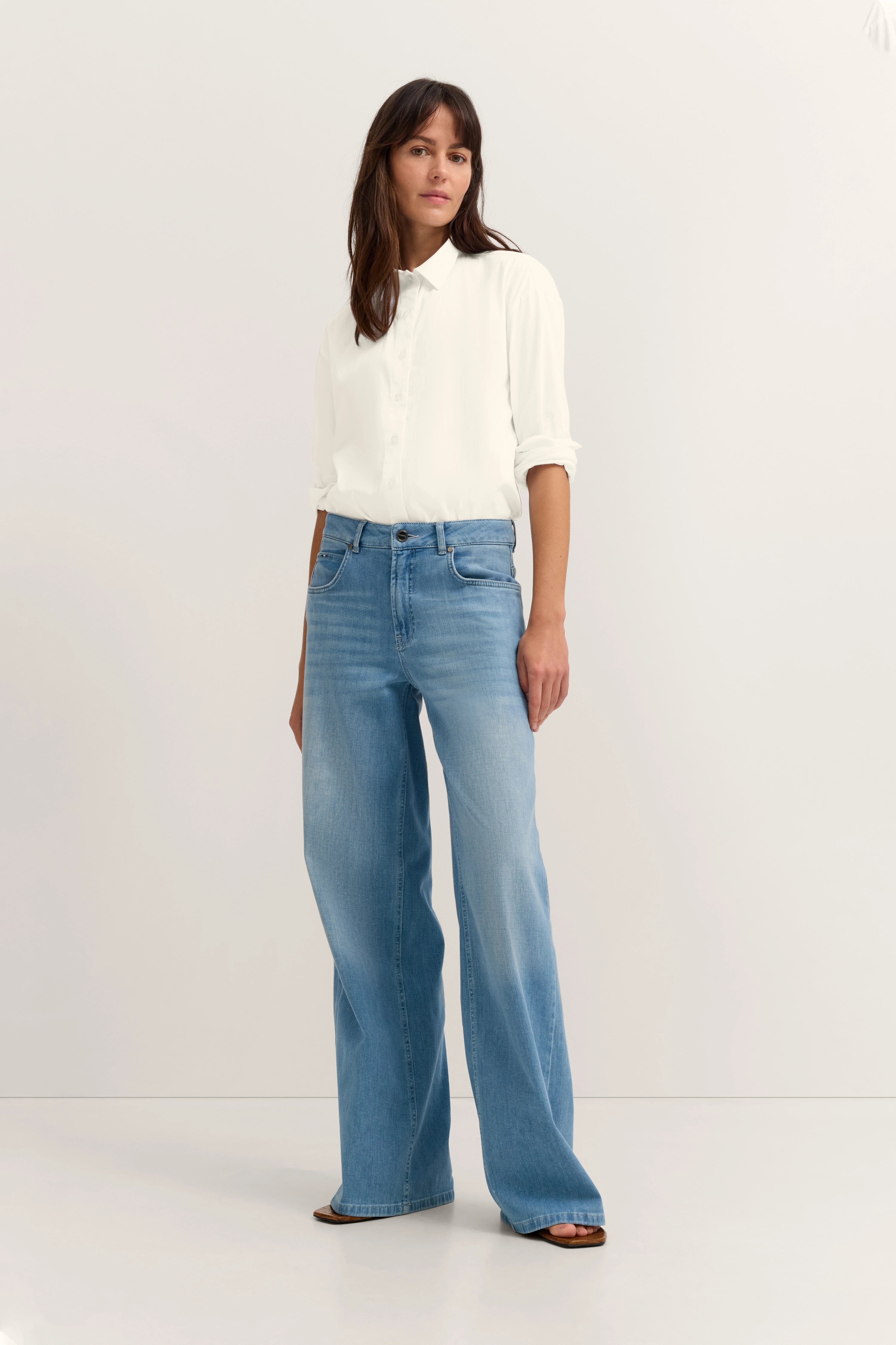 Weißes Hemd und blaue Jeans auf Model, locker stehend. bugatti Stil und Eleganz.