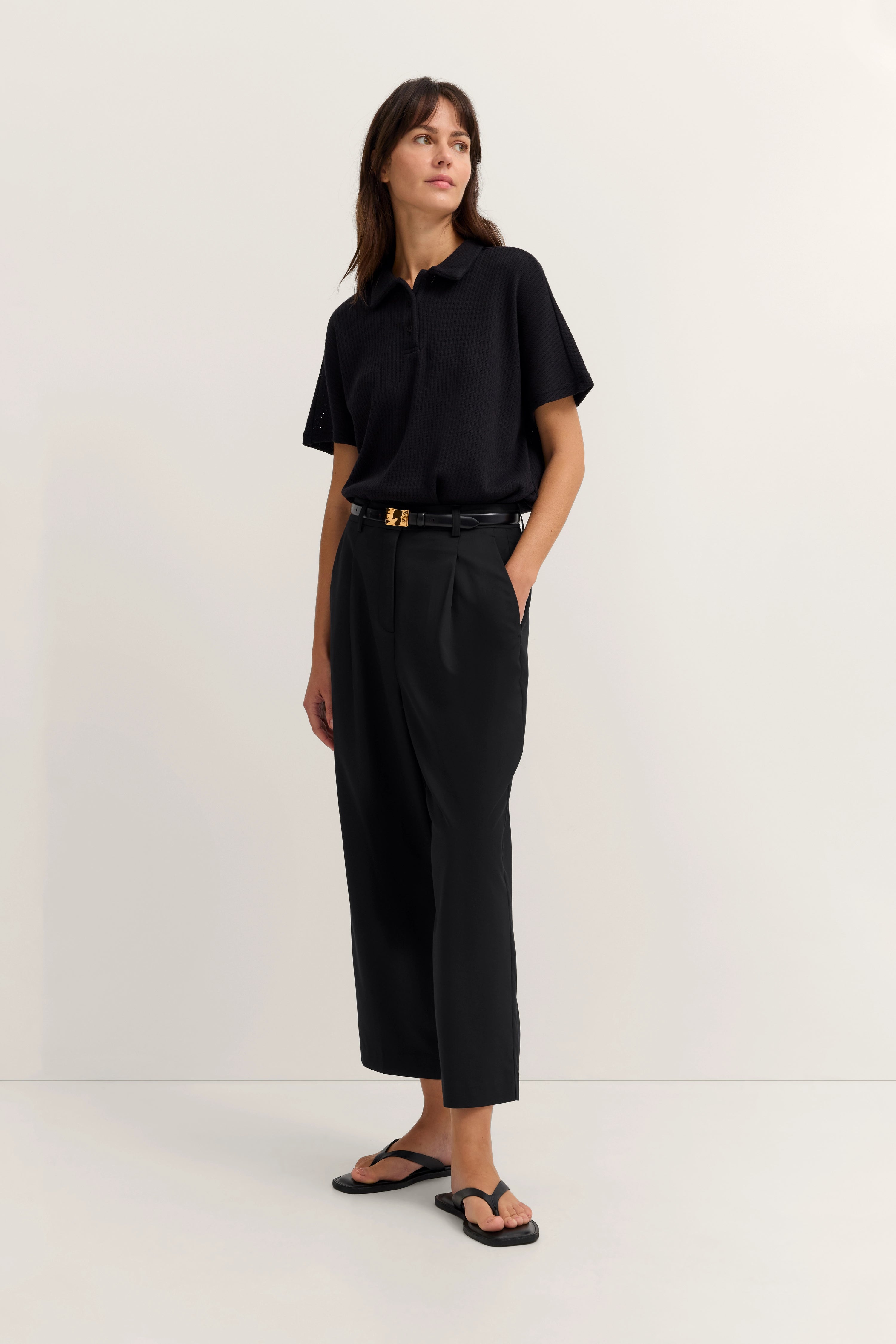 Schwarzes Polohemd und Hose von bugatti, Model posiert stehend, lässig und stilvoll.