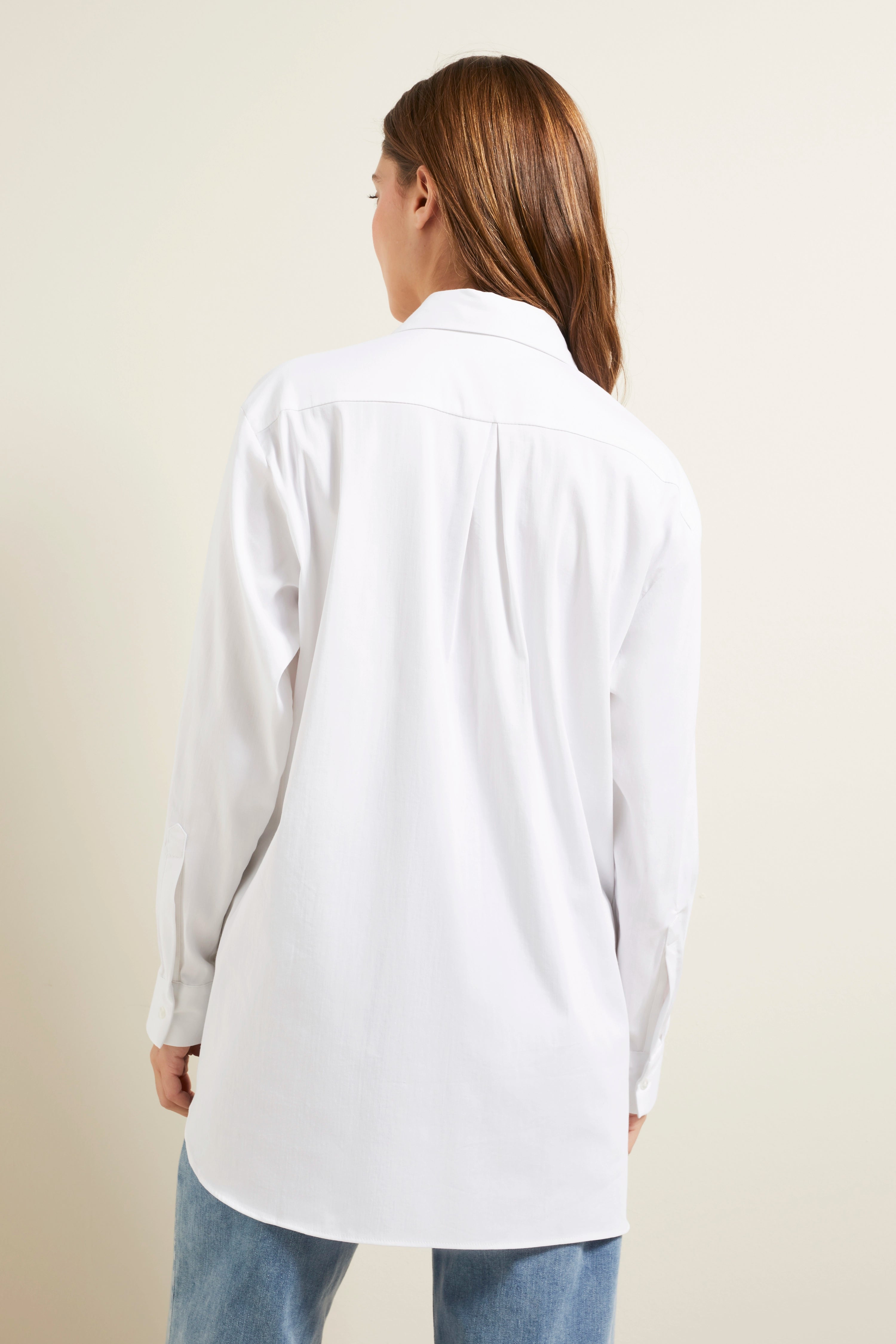 Weiße bugatti Bluse, lässig getragen, Rückansicht auf Model mit blauen Jeans.