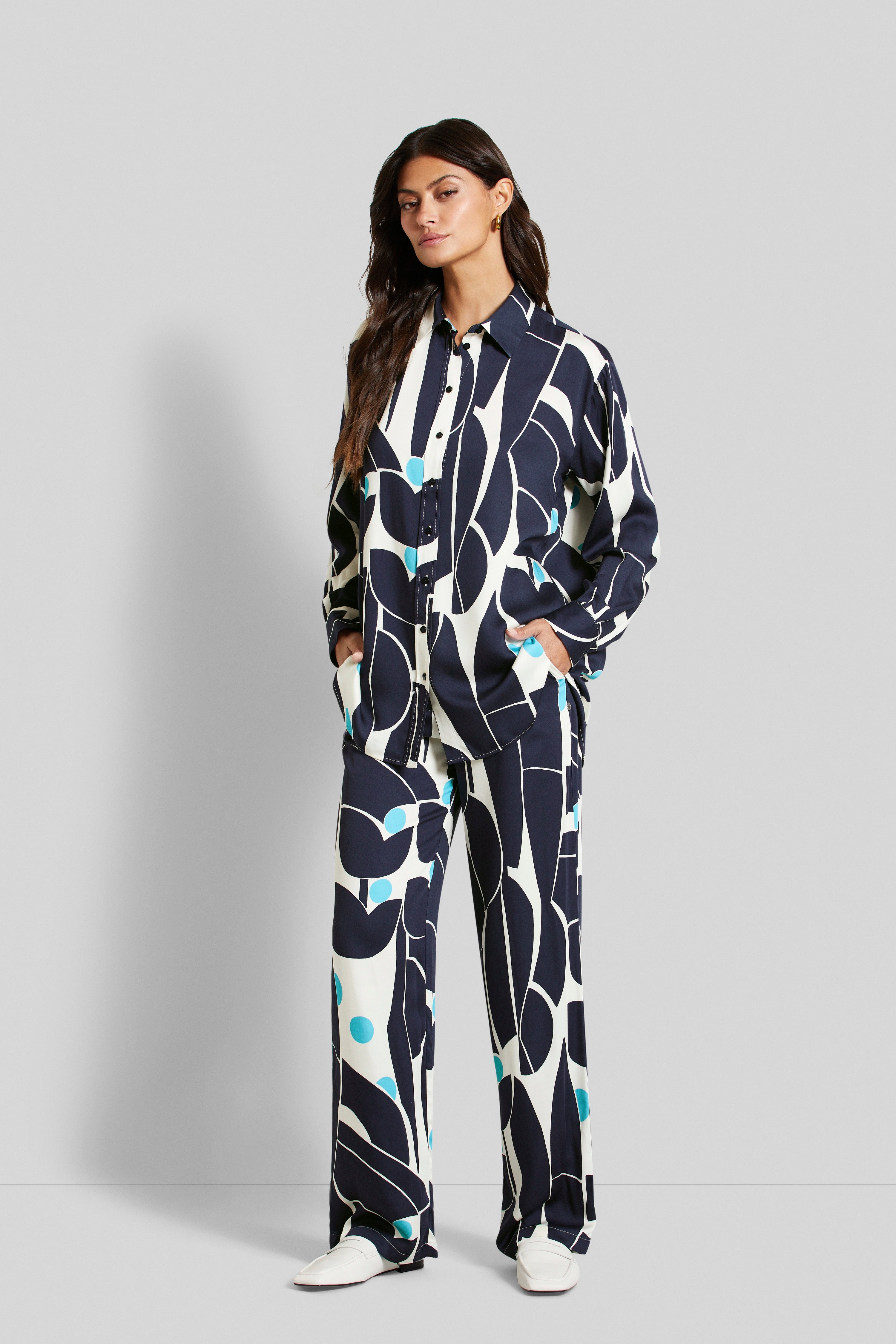 Model in patterned blue-white bugatti outfit, casual pose, hands in pockets.