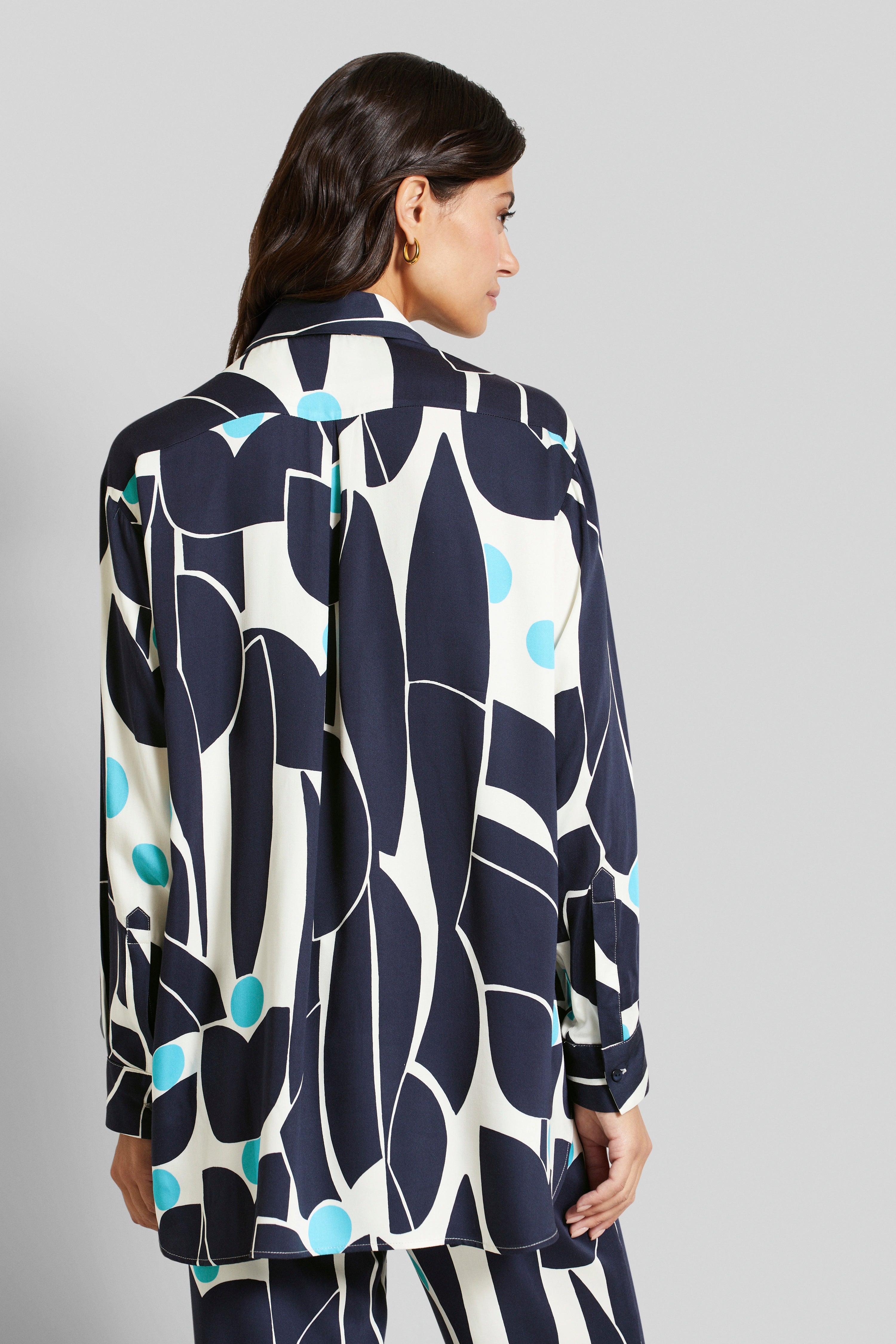 Model in bugatti shirt, blue-white, graphic pattern. Back view, casual pose.