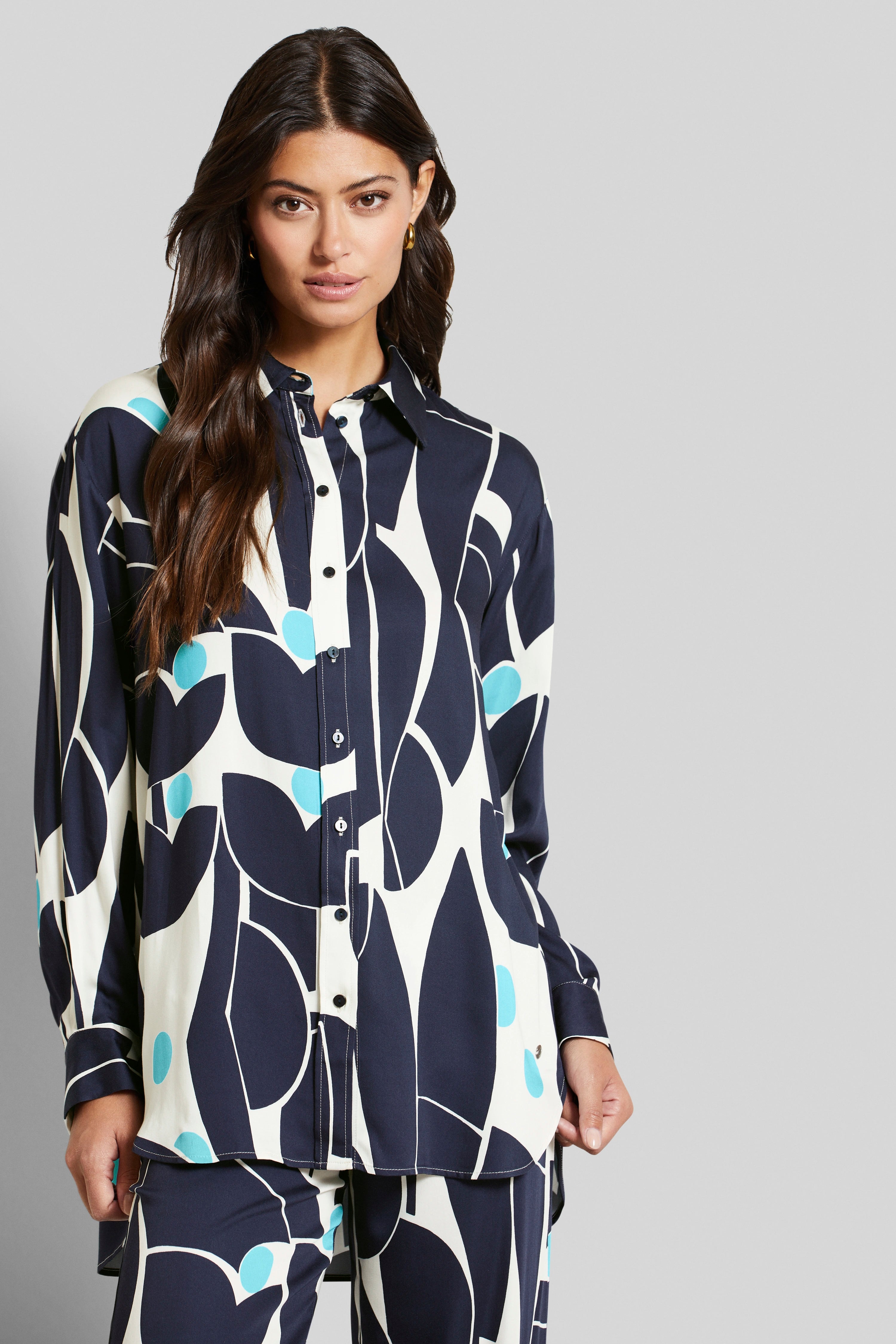 Model in bugatti outfit, black and white pattern with blue accents, relaxed pose.