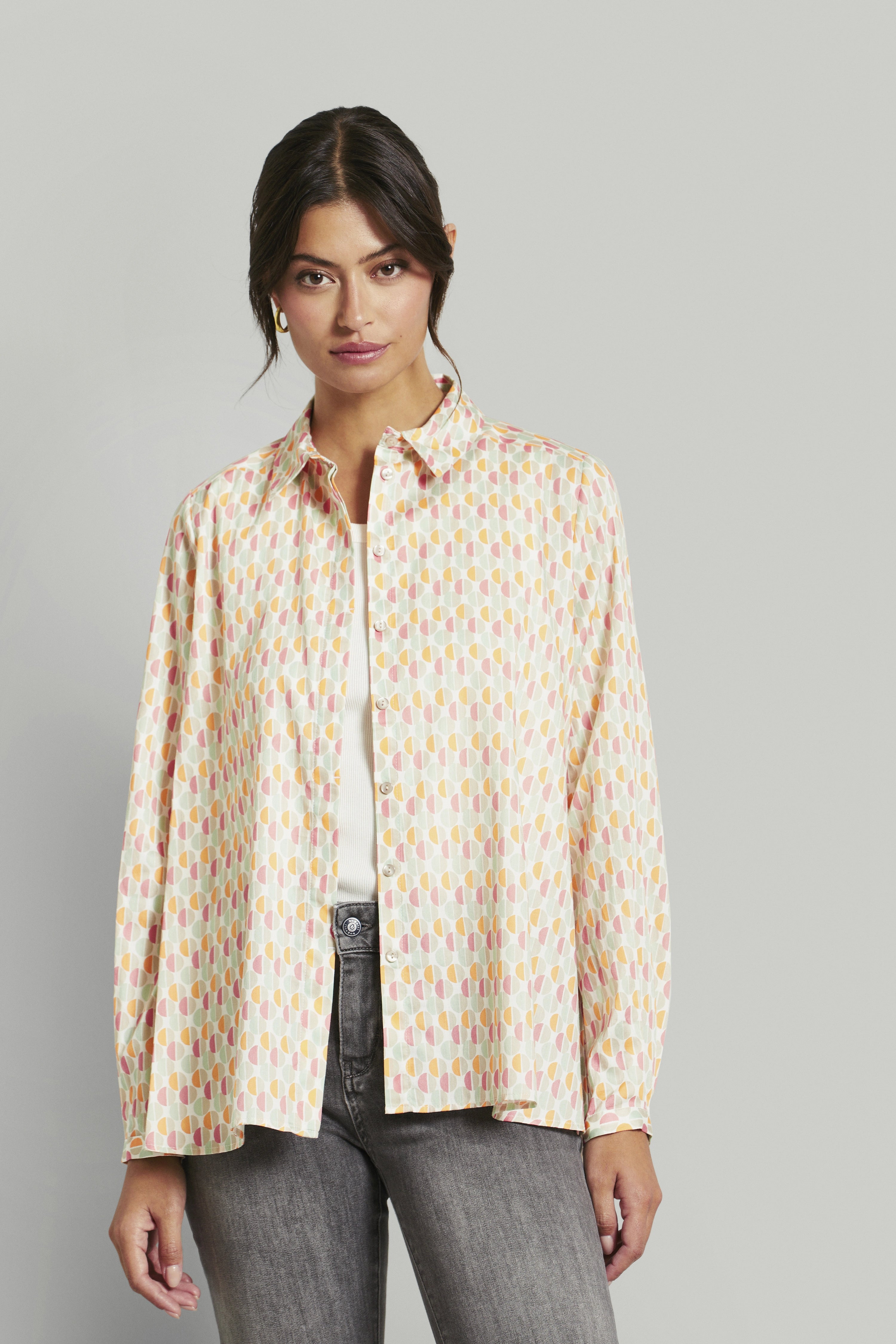 Bluse mit geometrischem Muster in Pastellfarben, Modelbild mit entspanntem, natürlichem Posing.