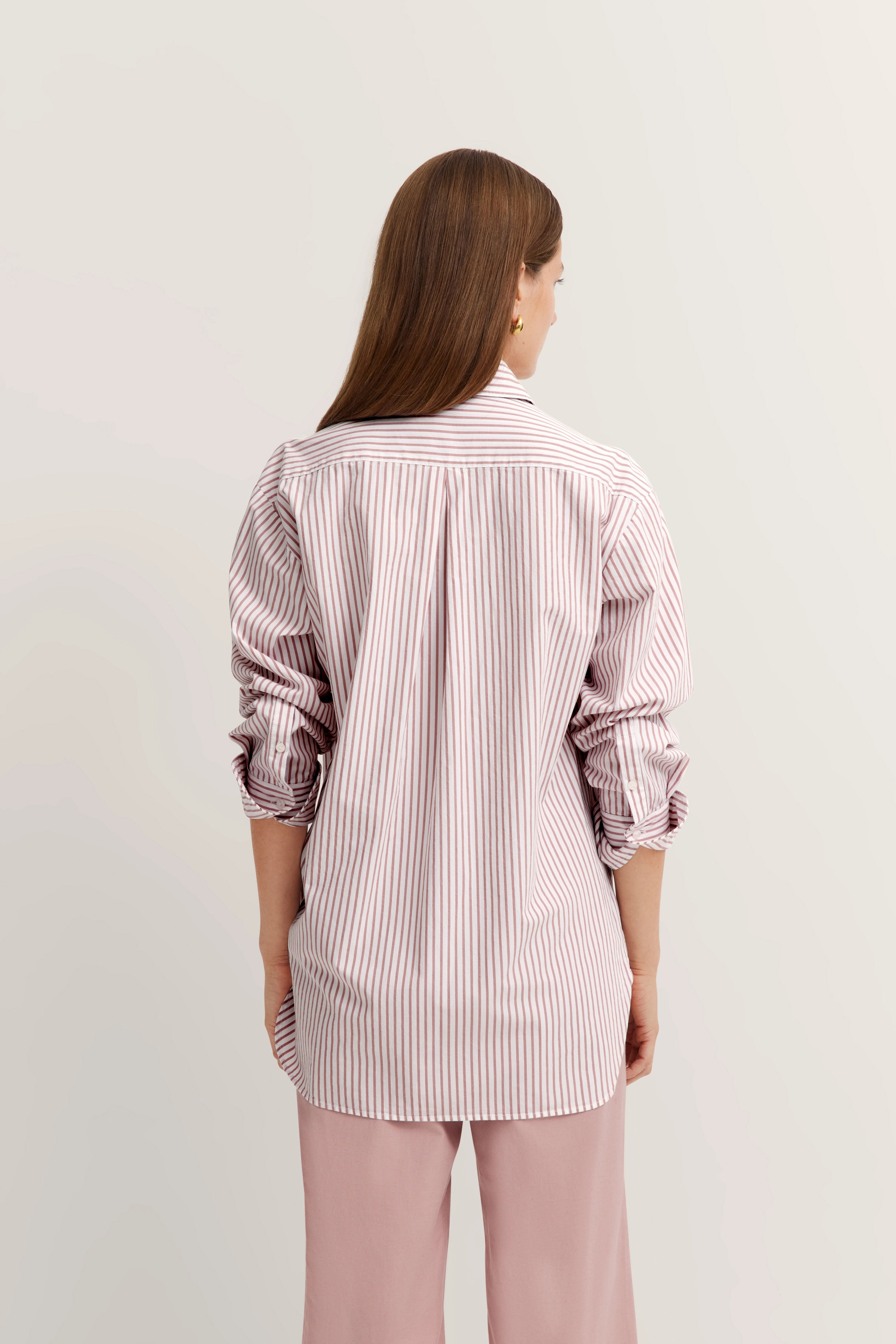 Büstenbild, gestreiftes Hemd in Weiß und Rosa, kombiniert mit rosa Hose, entspannter Rückenansicht.